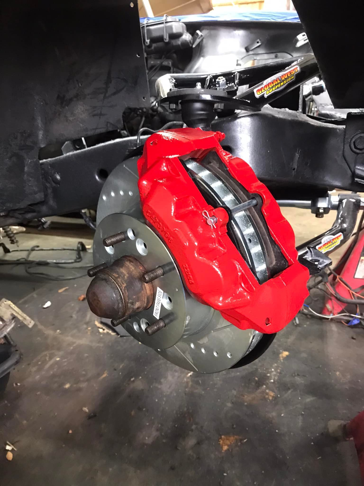 A red brake caliper is sitting on top of a black car.