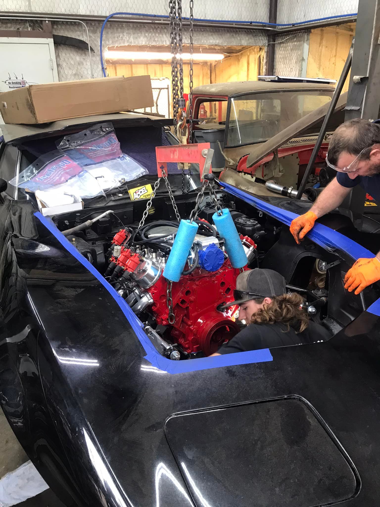 A man is working on a car engine in a garage.