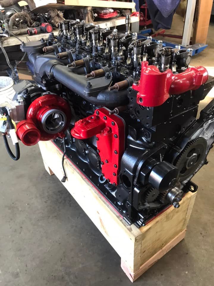 A black and red engine is sitting on top of a wooden box.