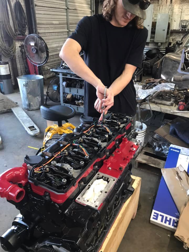A man is working on a red and black engine in a garage.