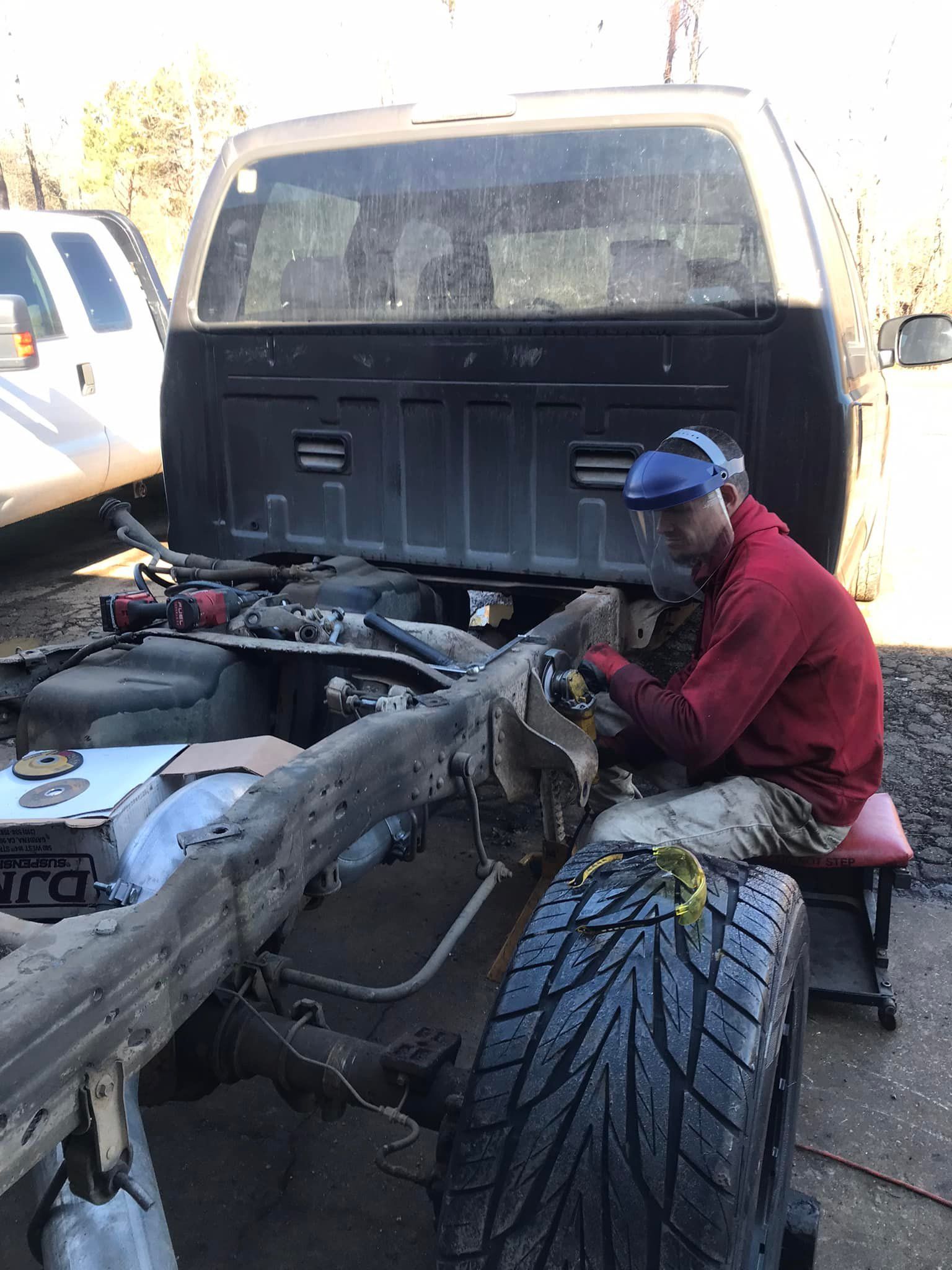 A man is working on the frame of a truck.