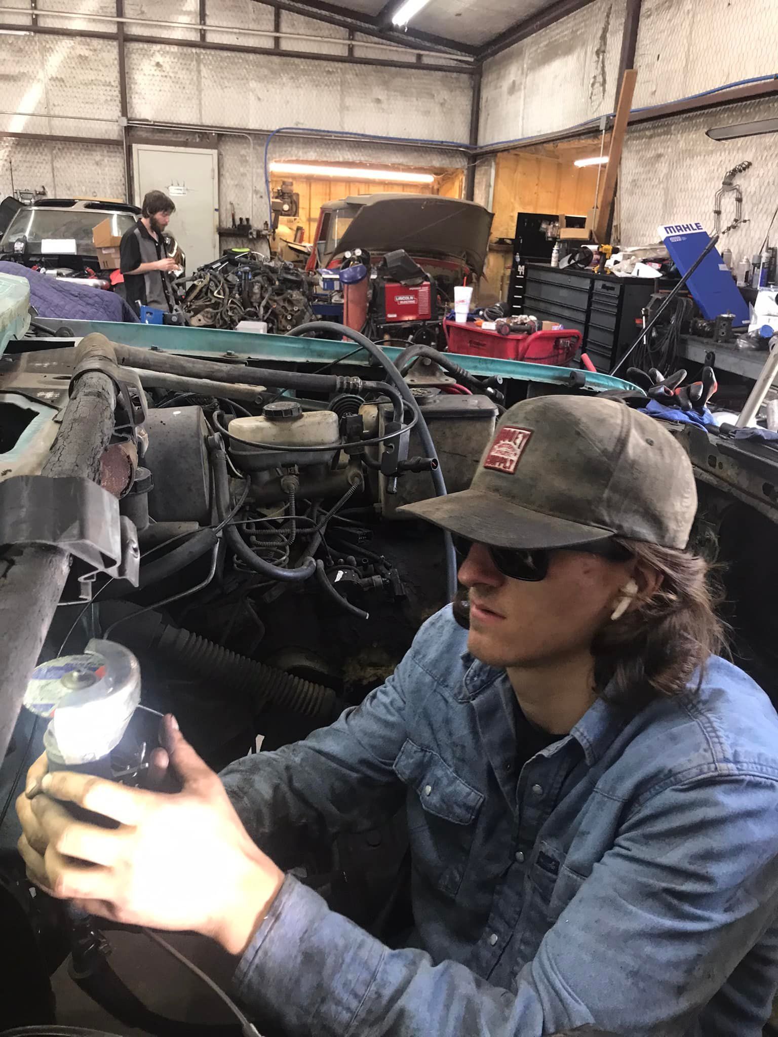 A man is working on a car engine in a garage.