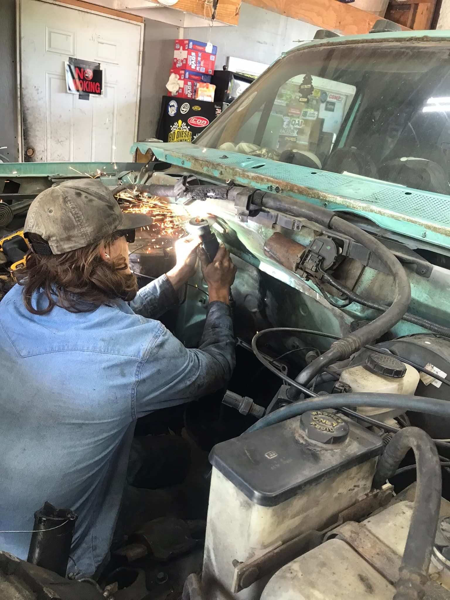 A man is working on the engine of a truck in a garage.
