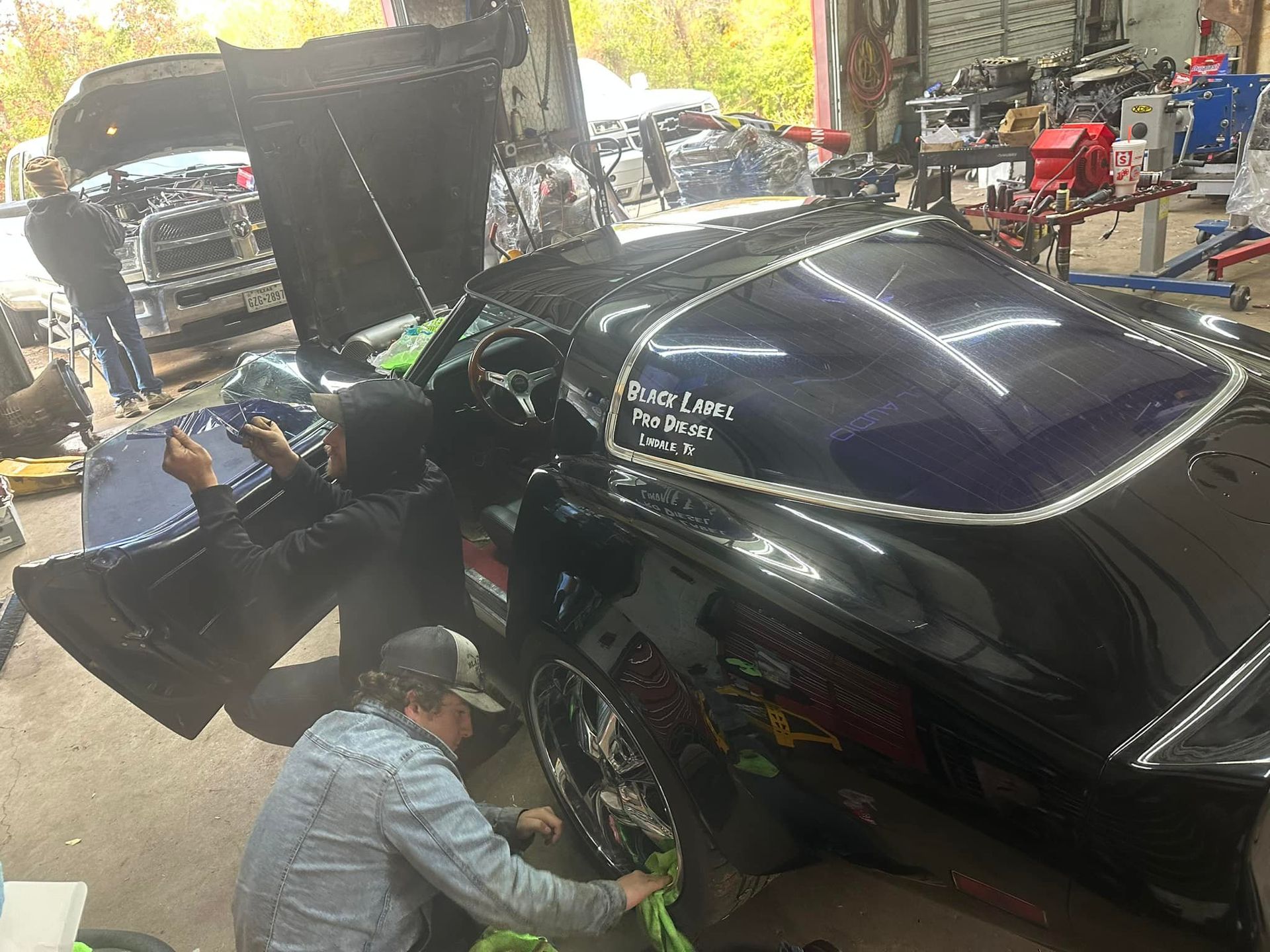 A man is working on a black car in a garage
