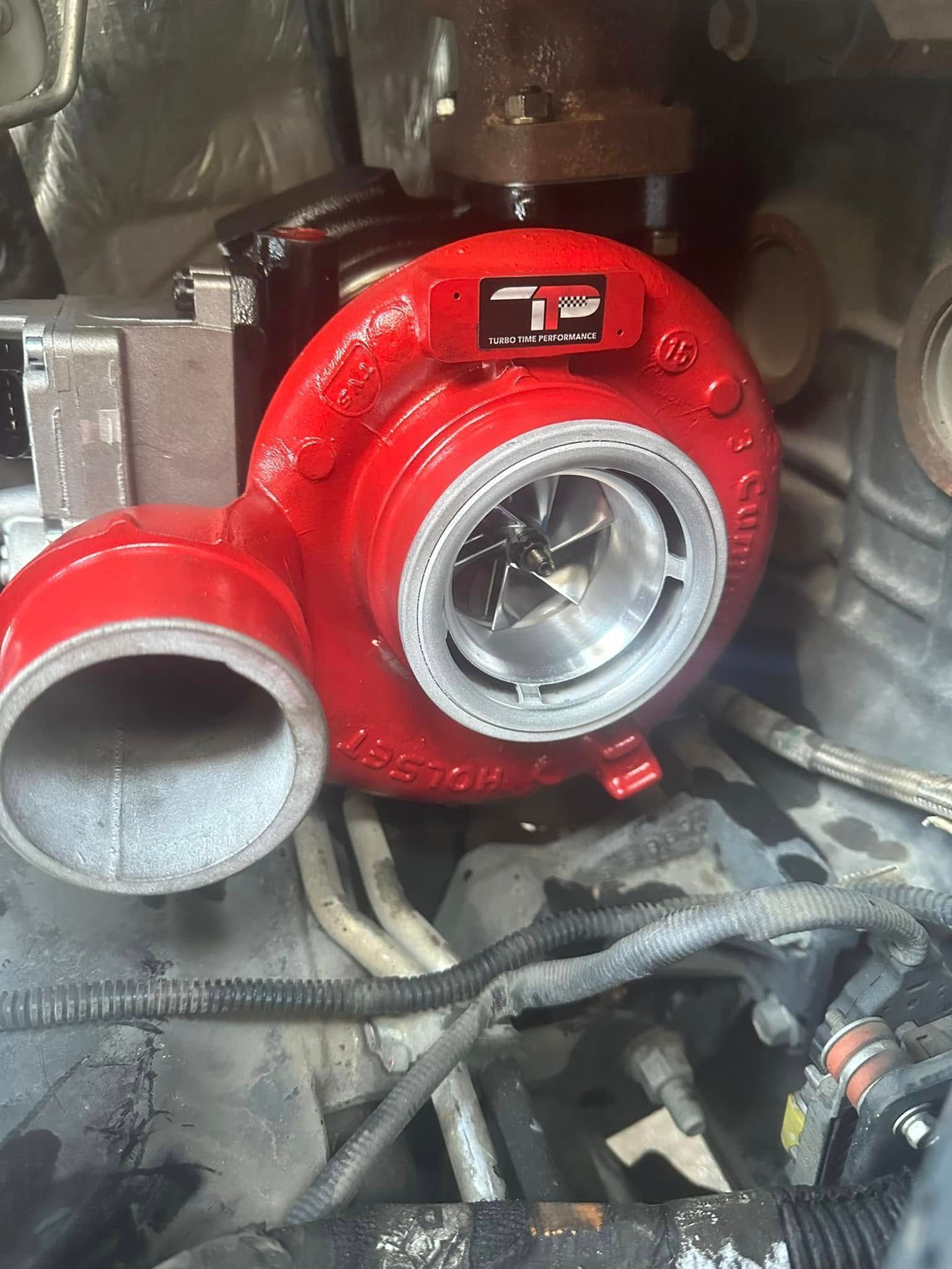 A red turbocharger is sitting inside of a car engine.