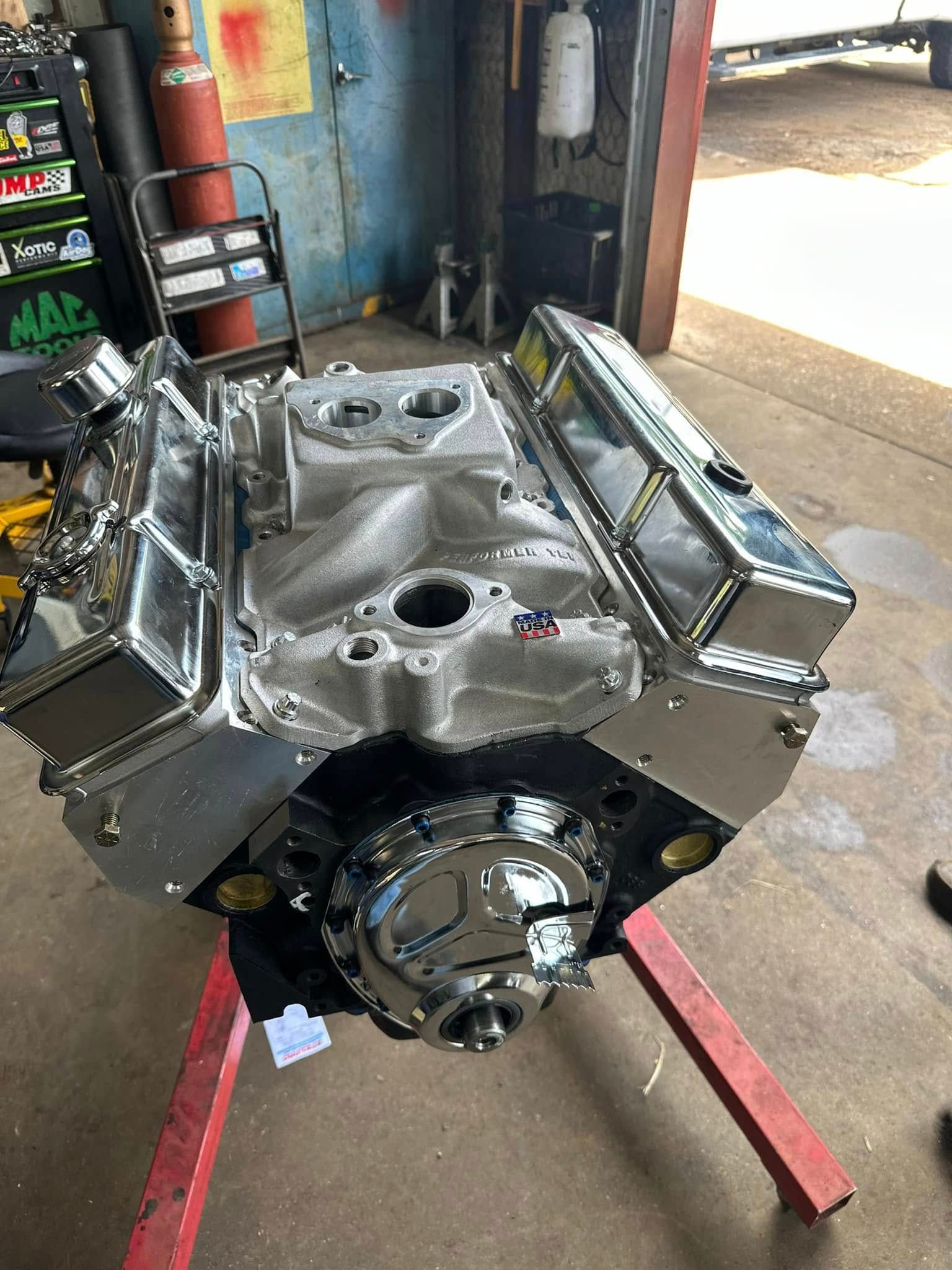 A car engine is sitting on a red stand in a garage.