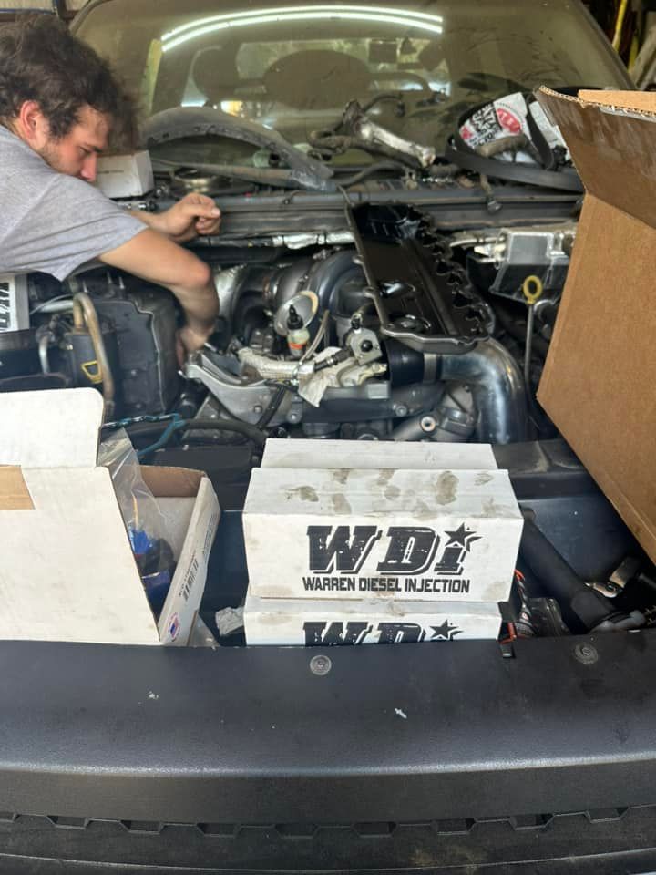A man is working on the engine of a car in a garage.