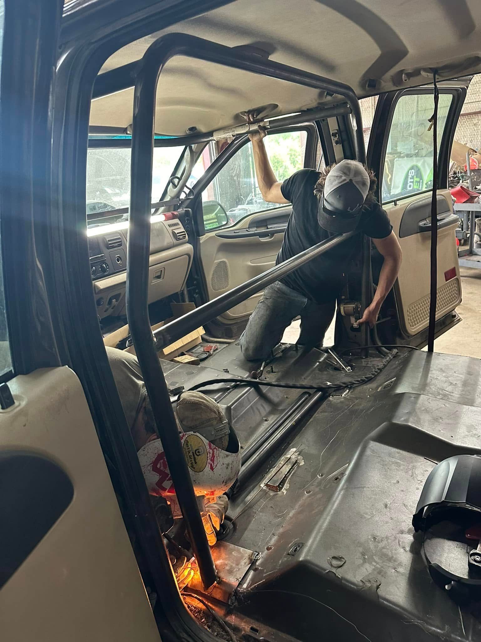 A man is working on the inside of a car in a garage.