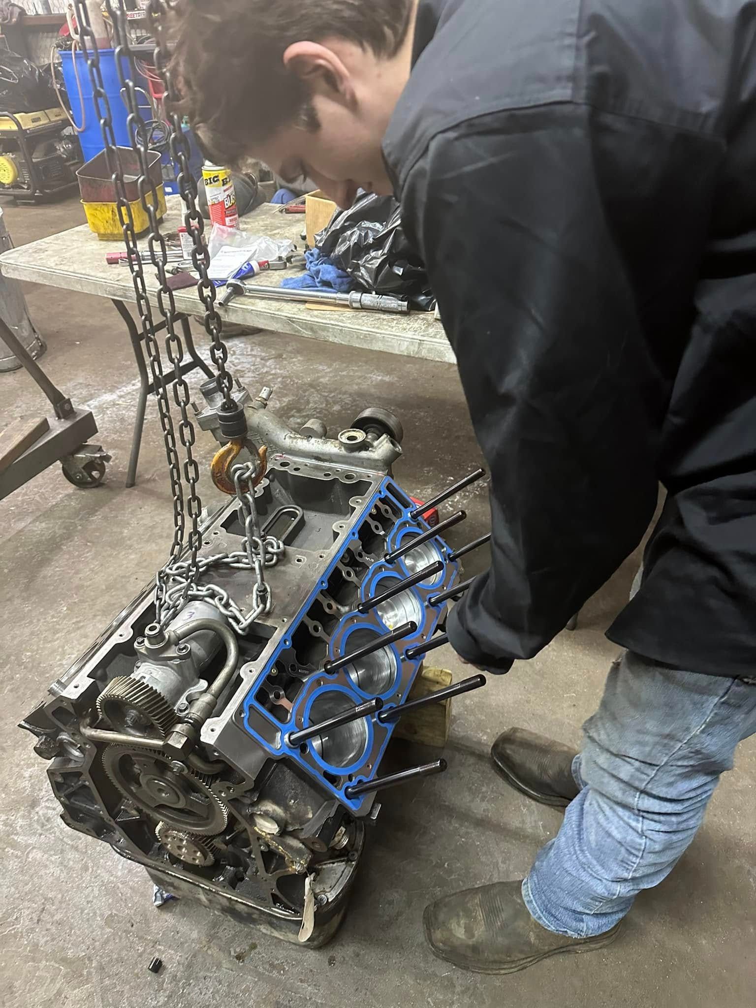 A man is working on a engine in a garage.