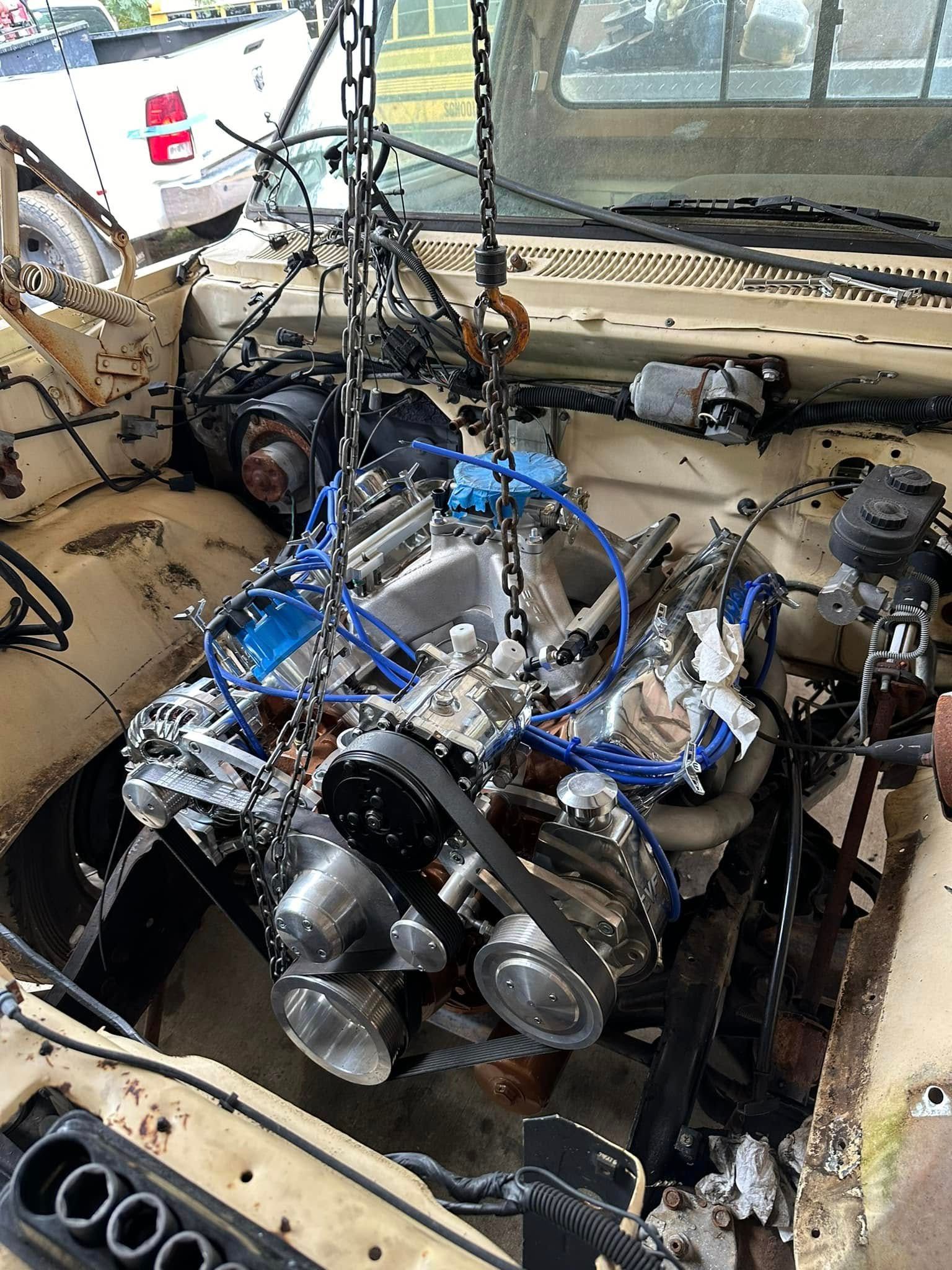 A car engine is being removed from the hood of a car.