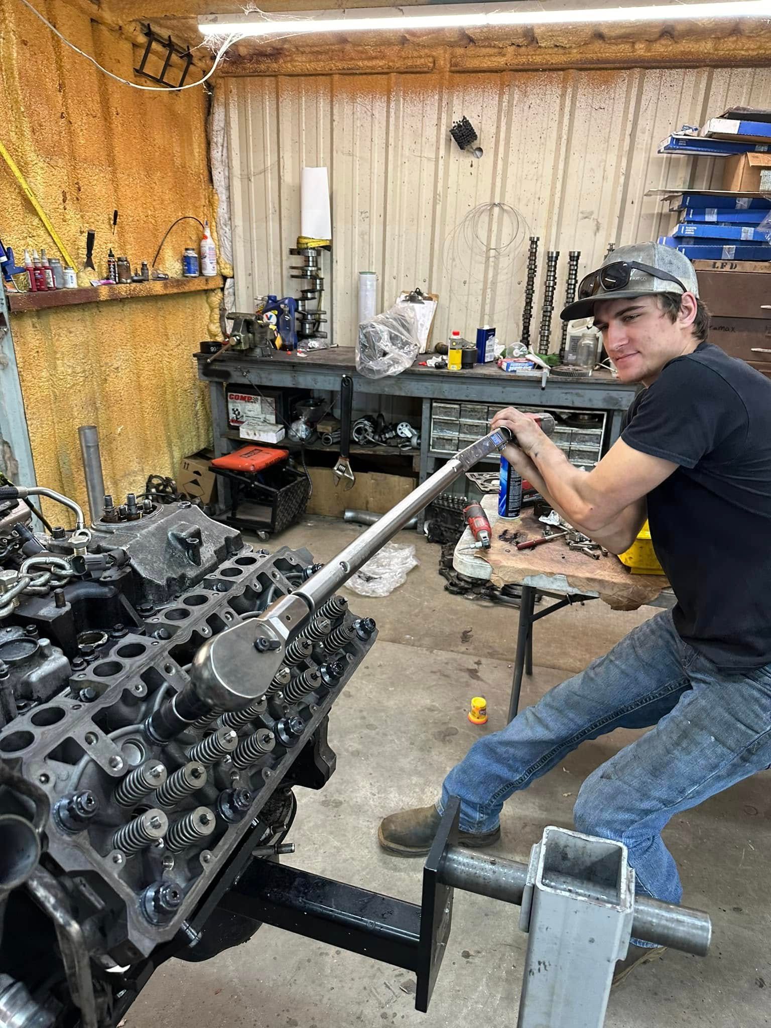 A man is working on a large engine in a garage.