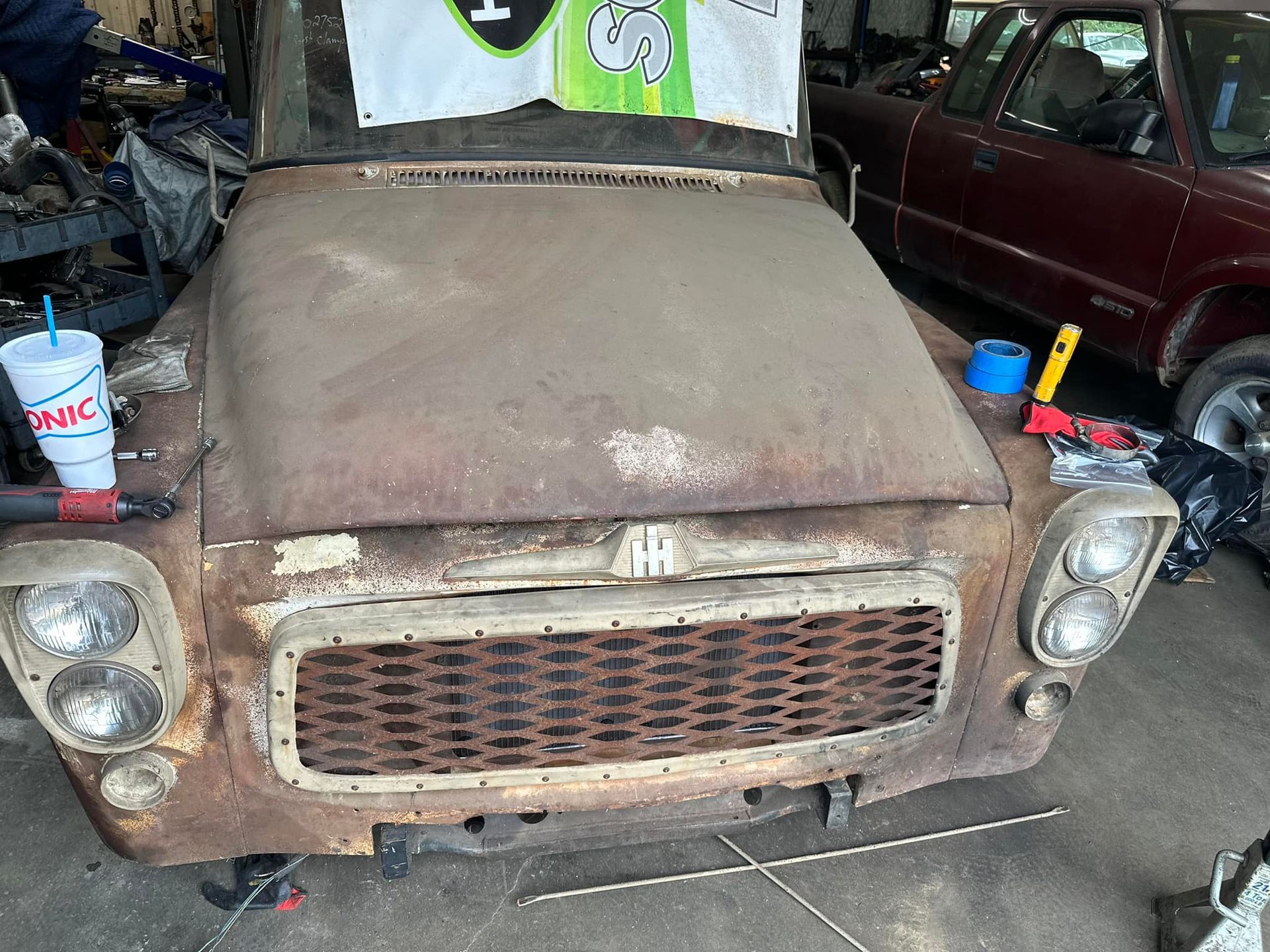 An old rusty car is sitting in a garage.