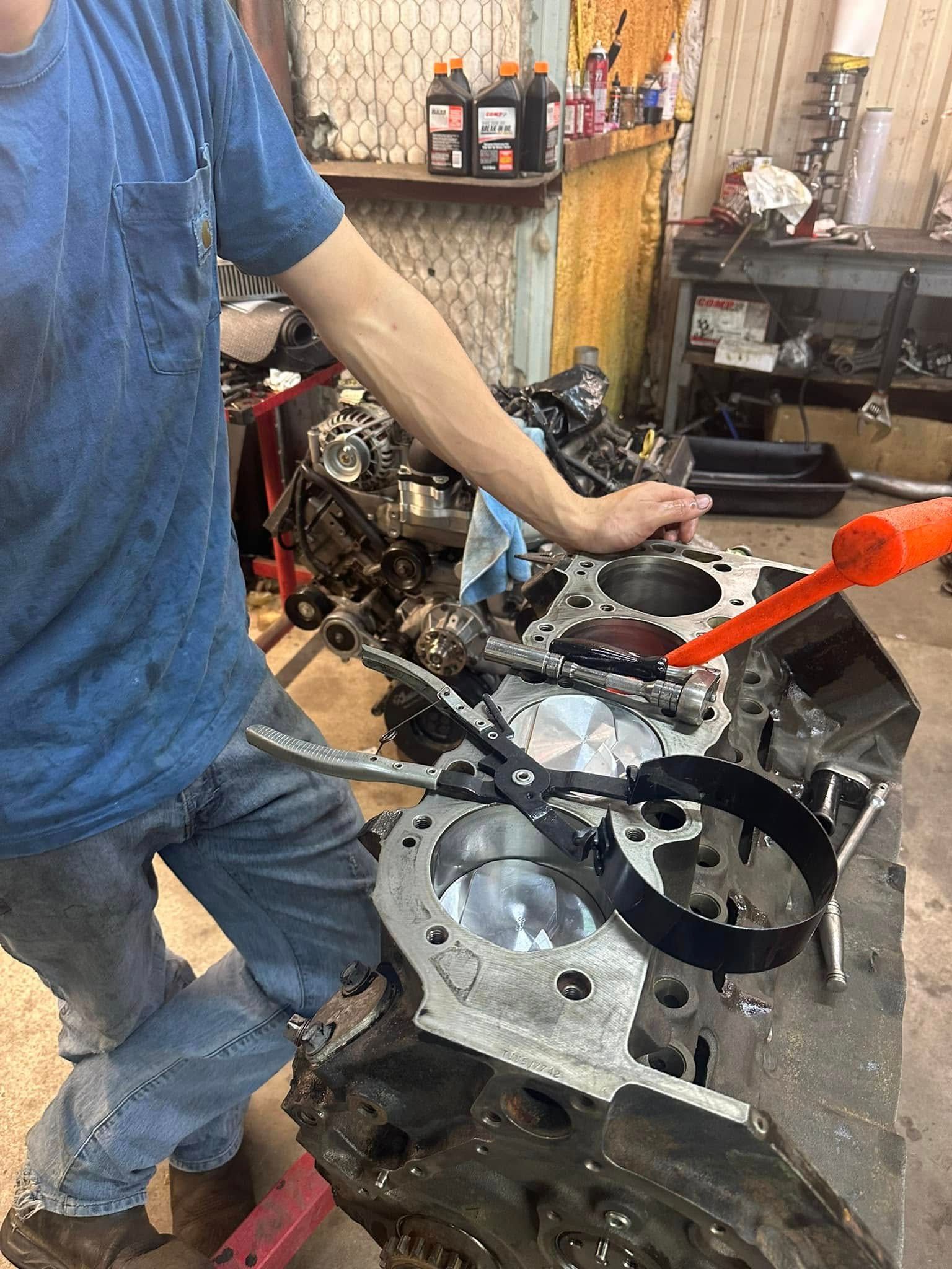 A man is working on a car engine in a garage.