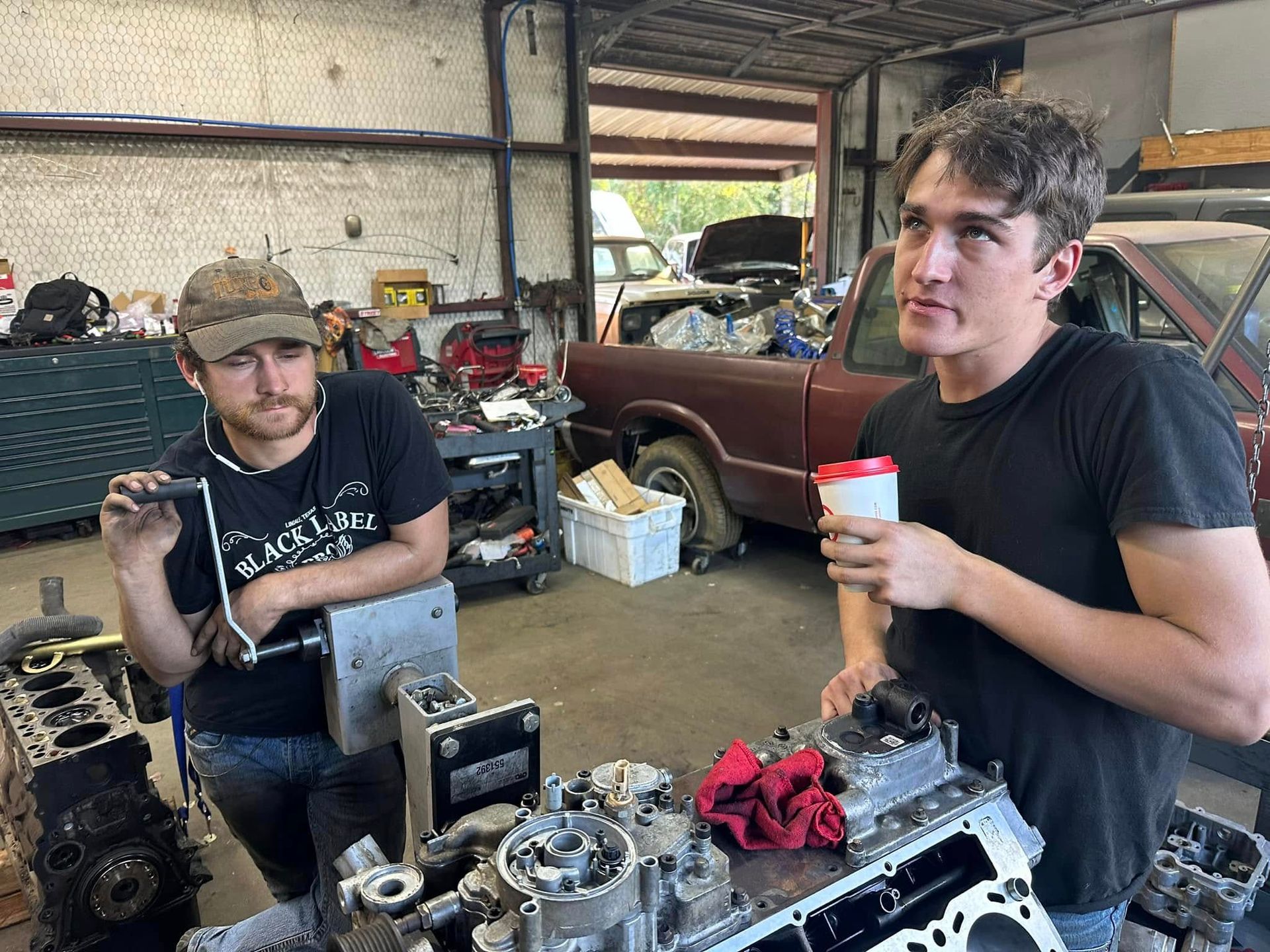 Two men are working on a car engine in a garage.