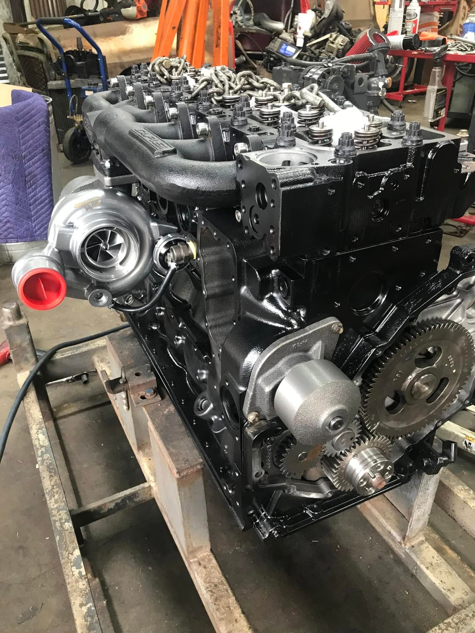 A black engine is sitting on top of a wooden pallet in a garage.