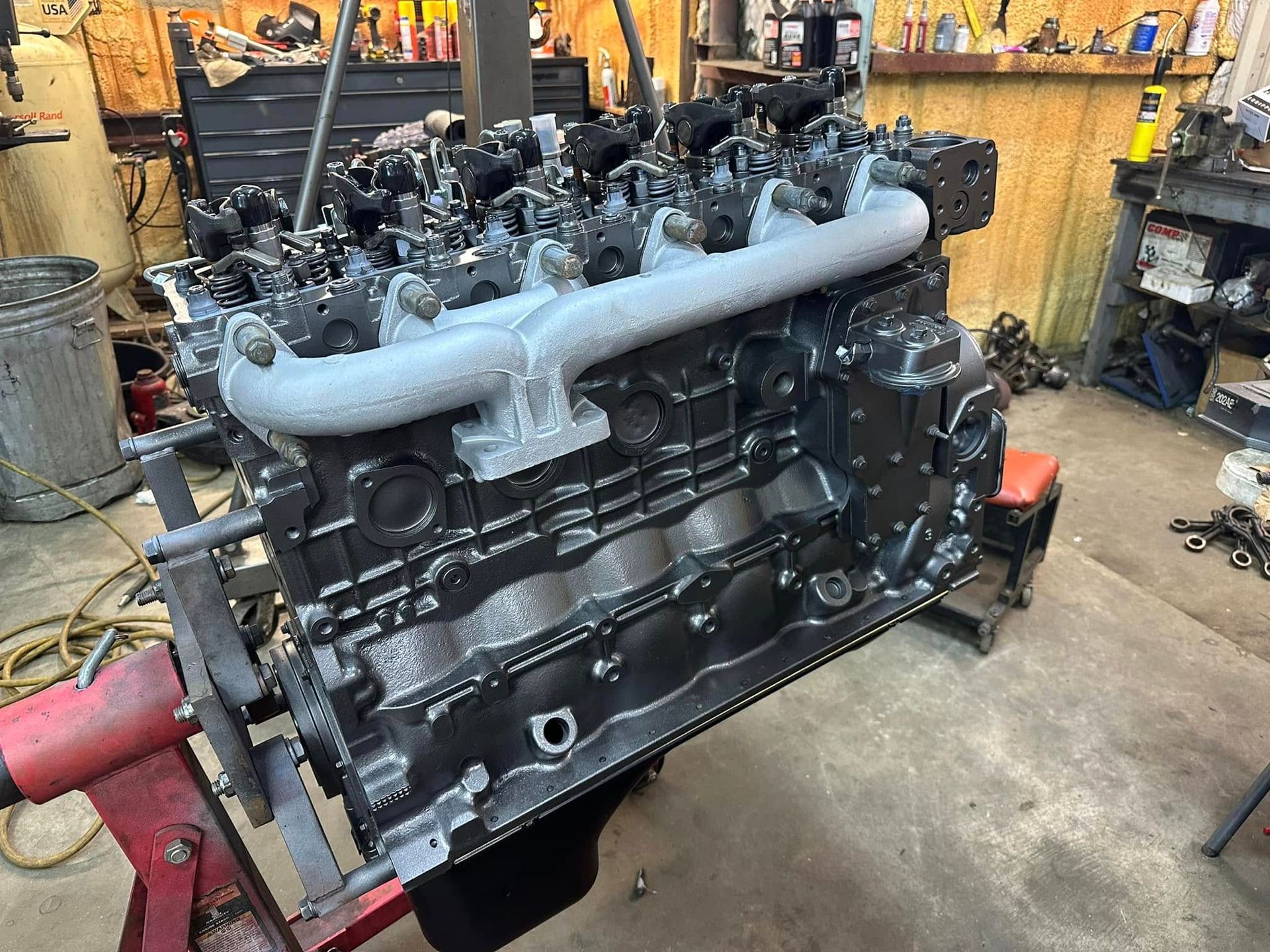 A black engine is sitting on top of a red stand in a garage.