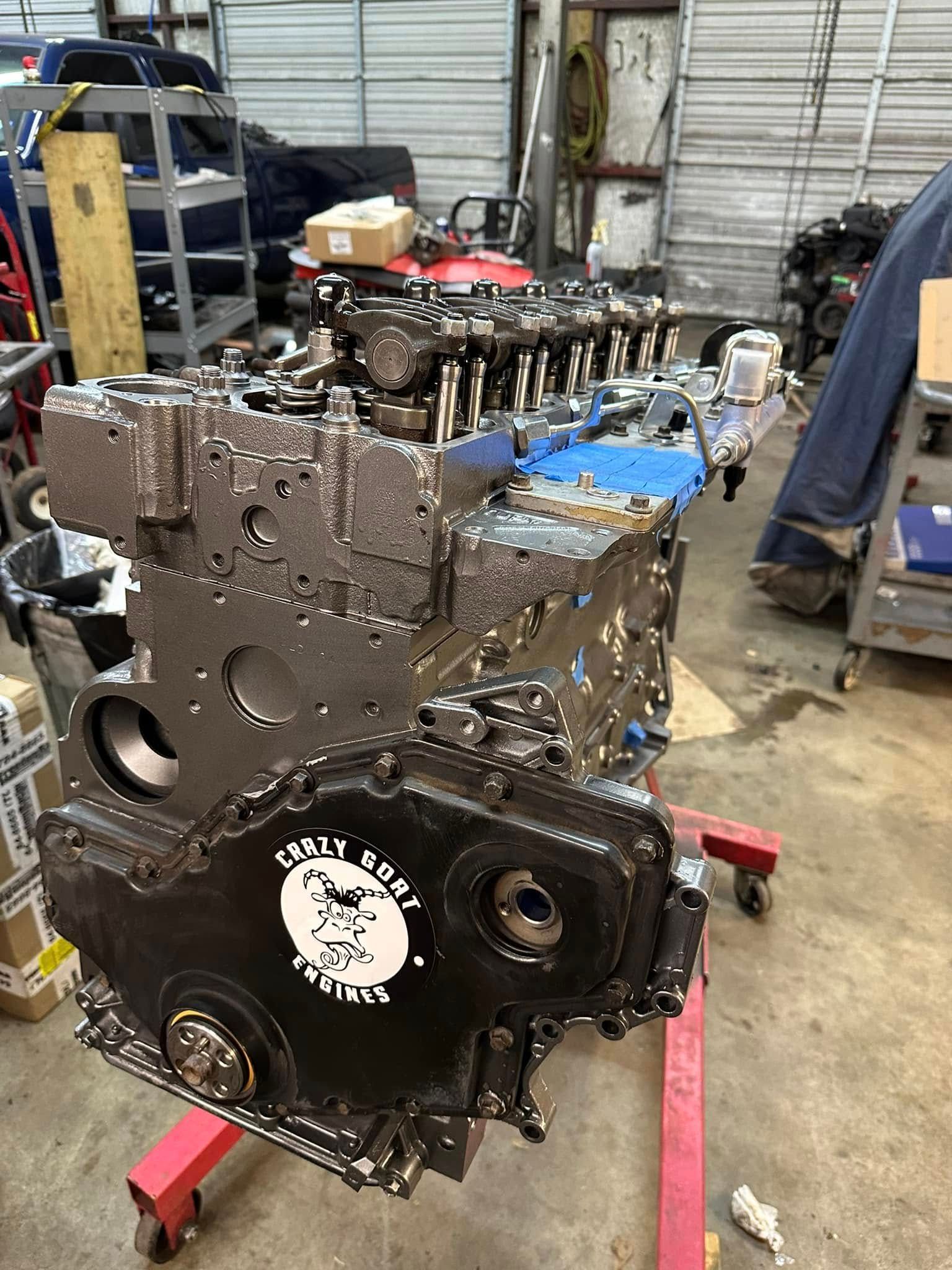 A large engine is sitting on top of a red dolly in a garage.