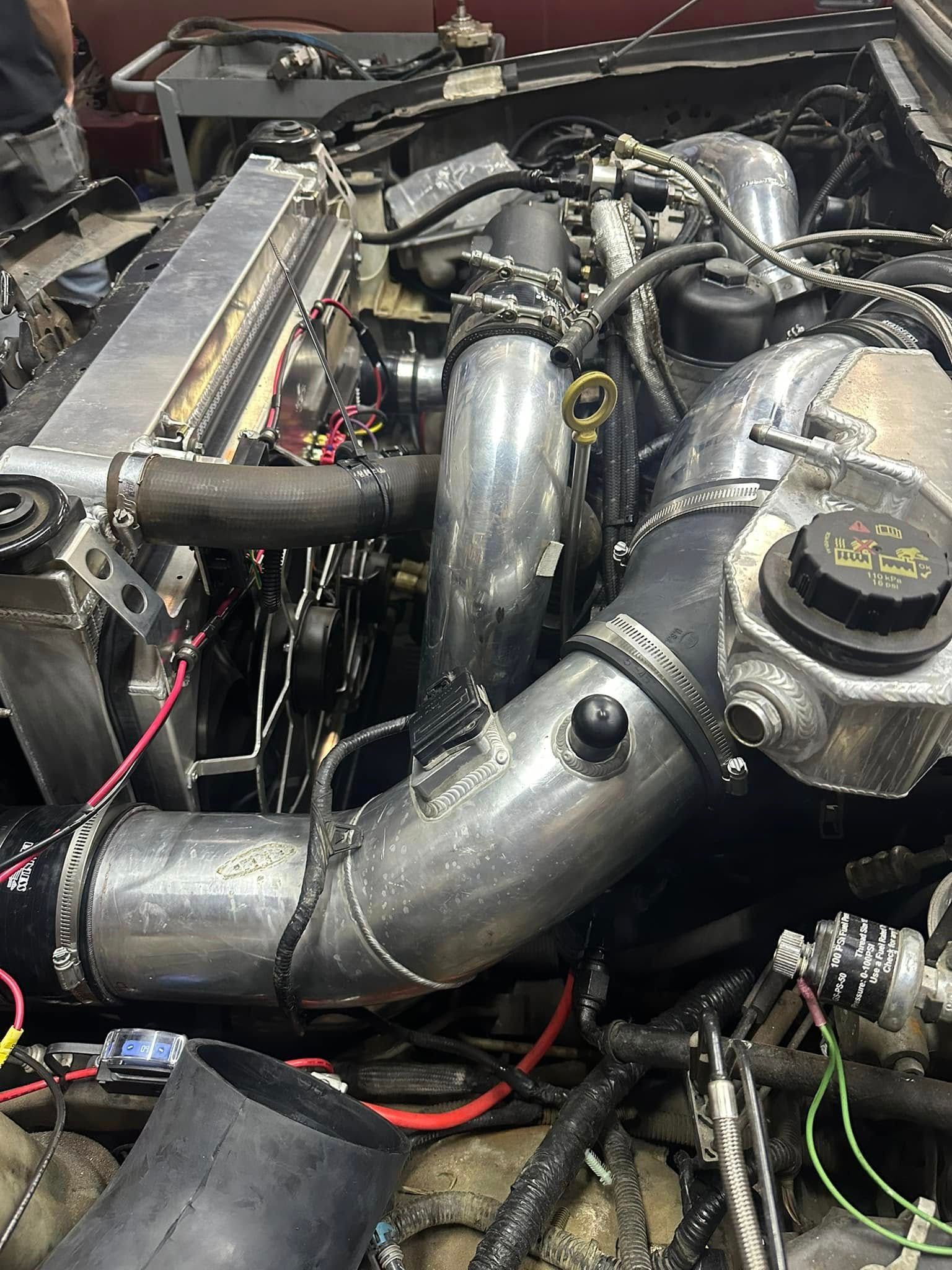 A close up of a car engine with a lot of wires coming out of it.