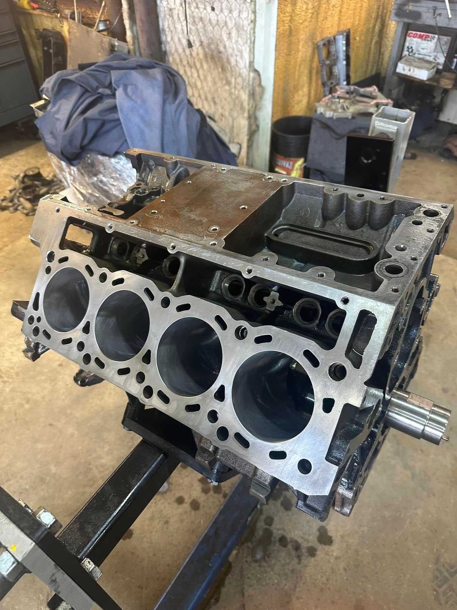A cylinder block is sitting on top of a metal stand in a garage.