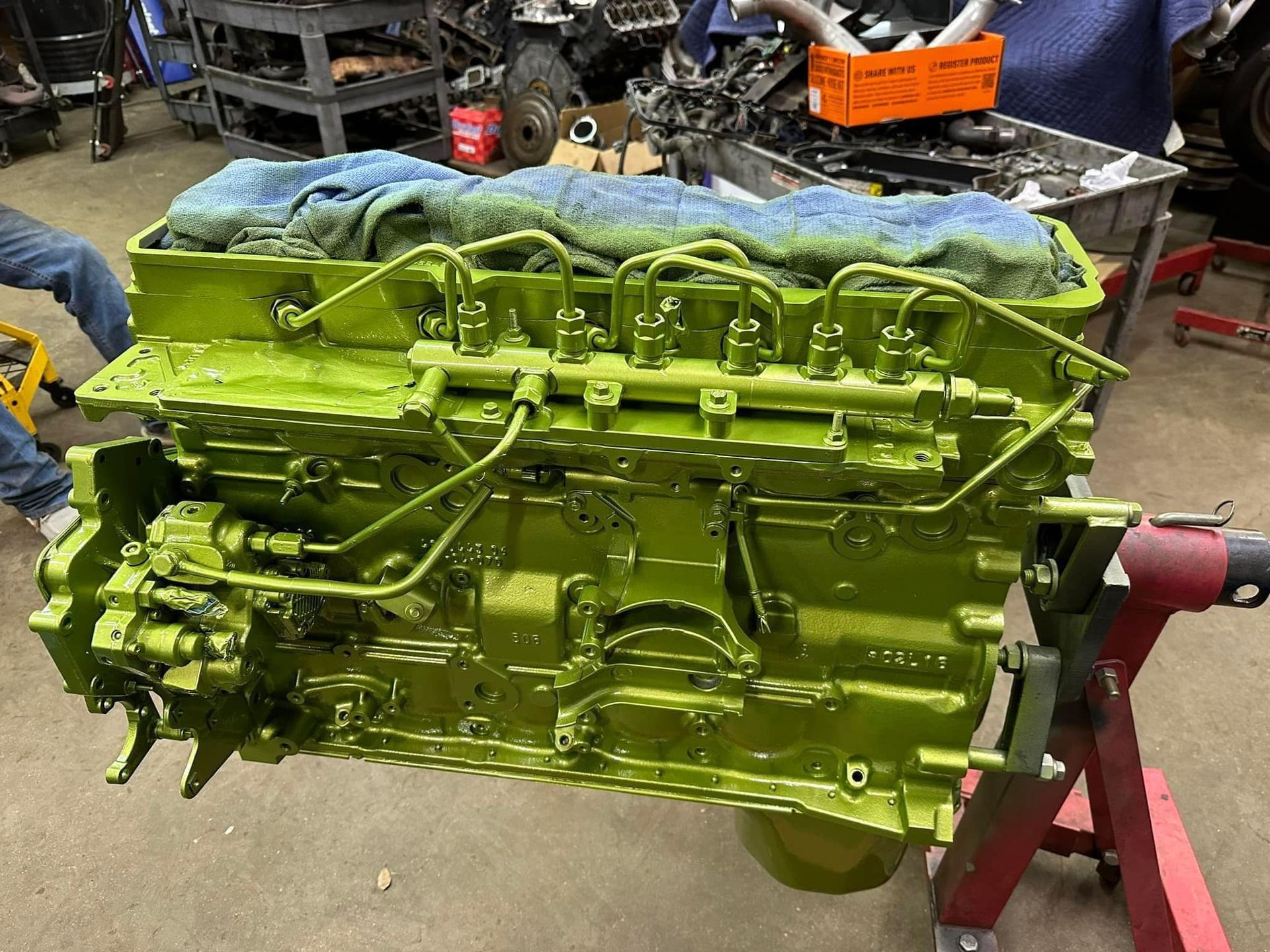 A green engine is sitting on a stand in a garage.