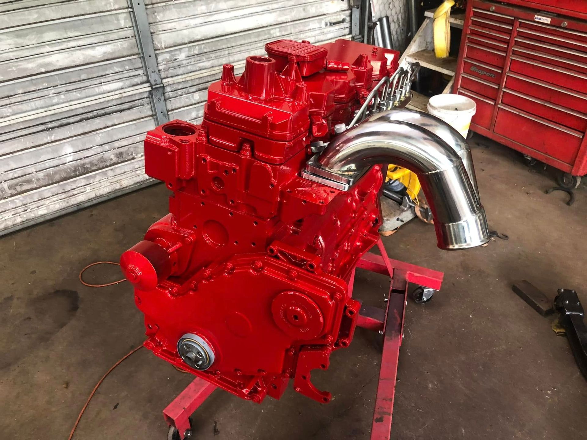 A red engine is sitting on a red stand in a garage.
