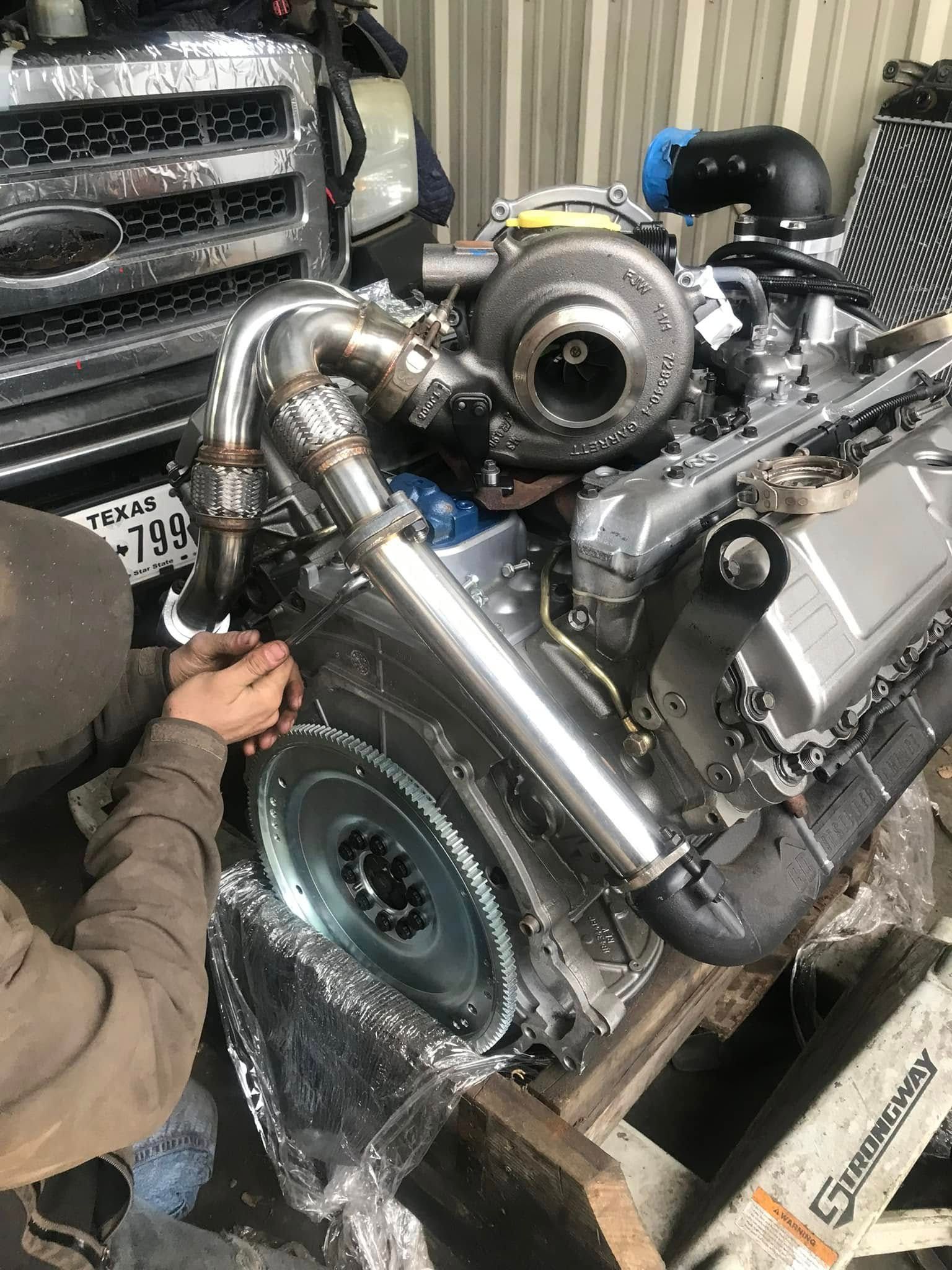 A man is working on a diesel engine in a garage.