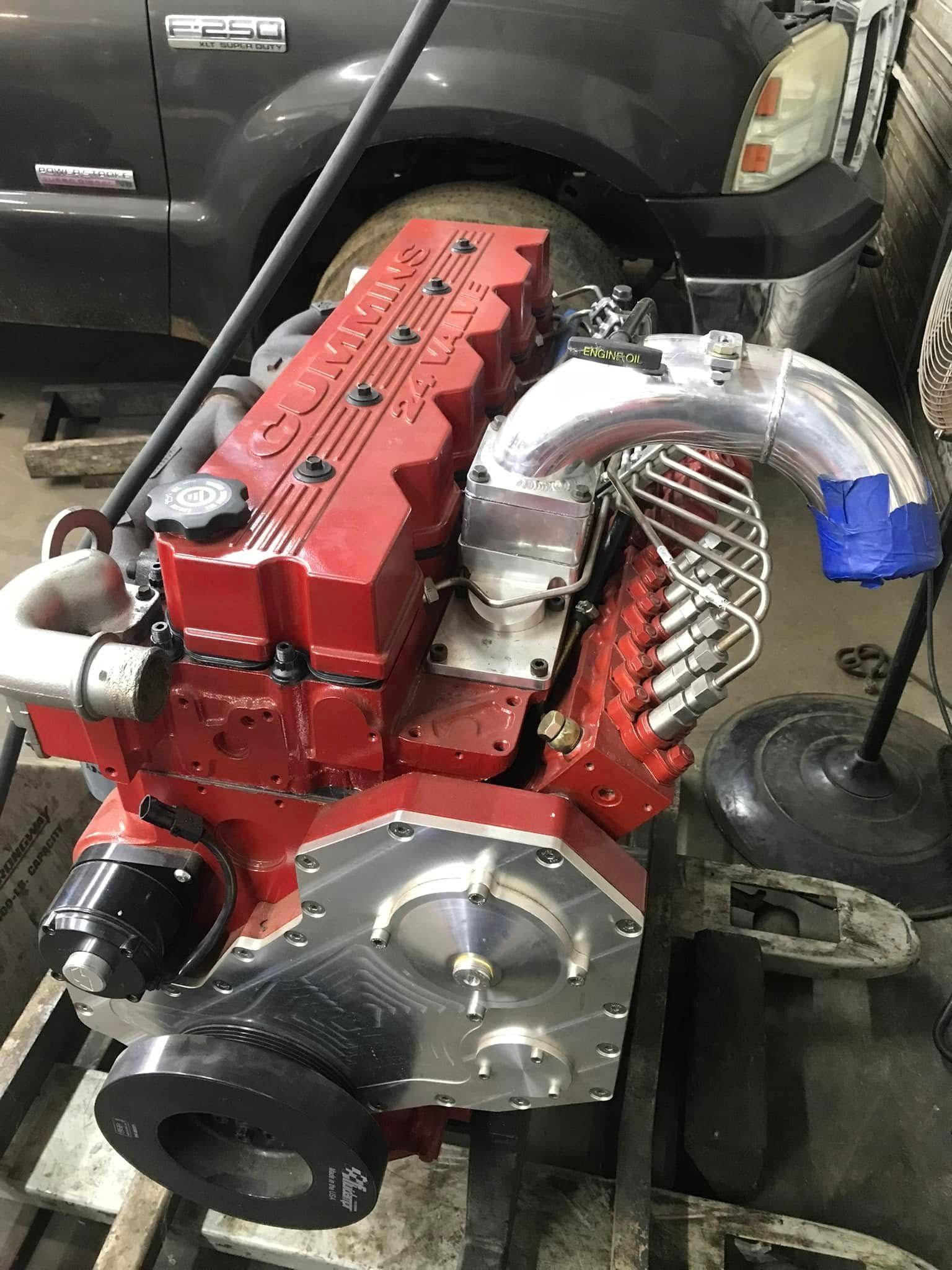 A red engine is sitting on a table in front of a truck.