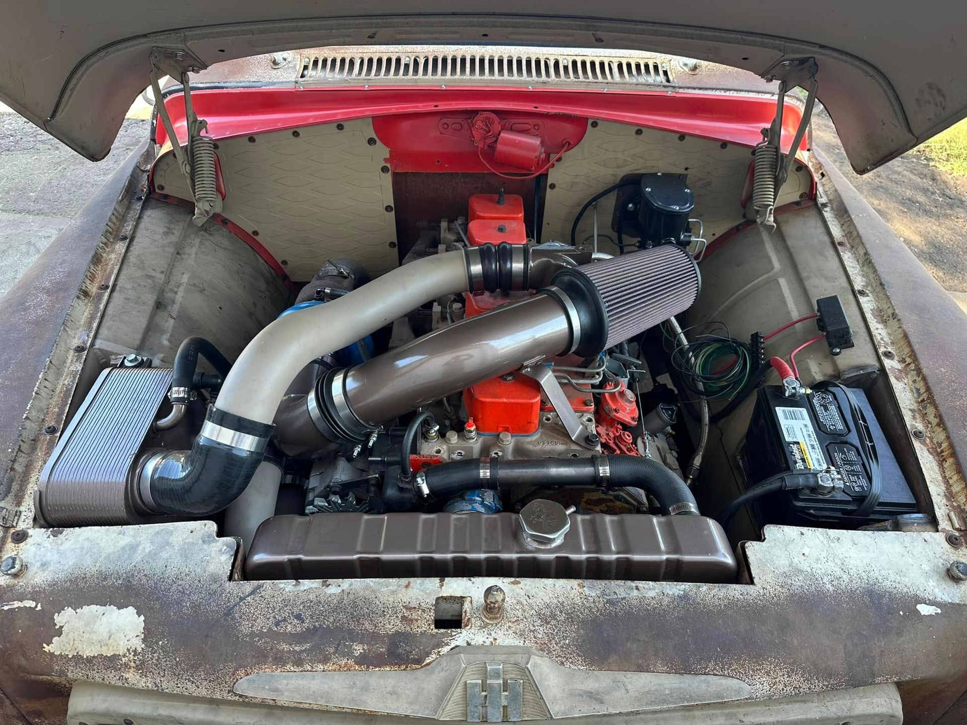 The hood of an old rusty car with the engine exposed