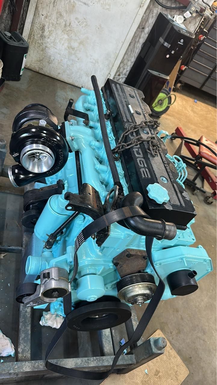 A blue engine is sitting on top of a metal stand in a garage.