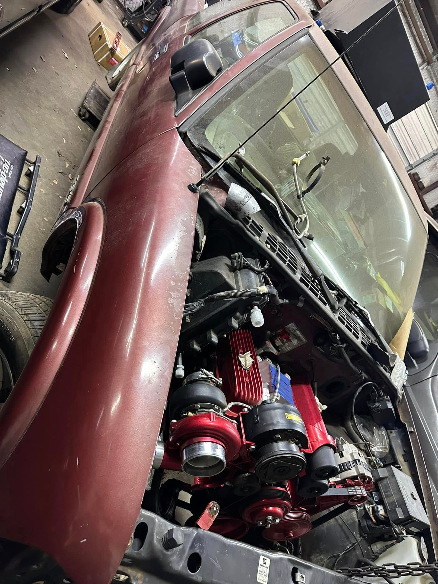 A red truck with its hood open in a garage.