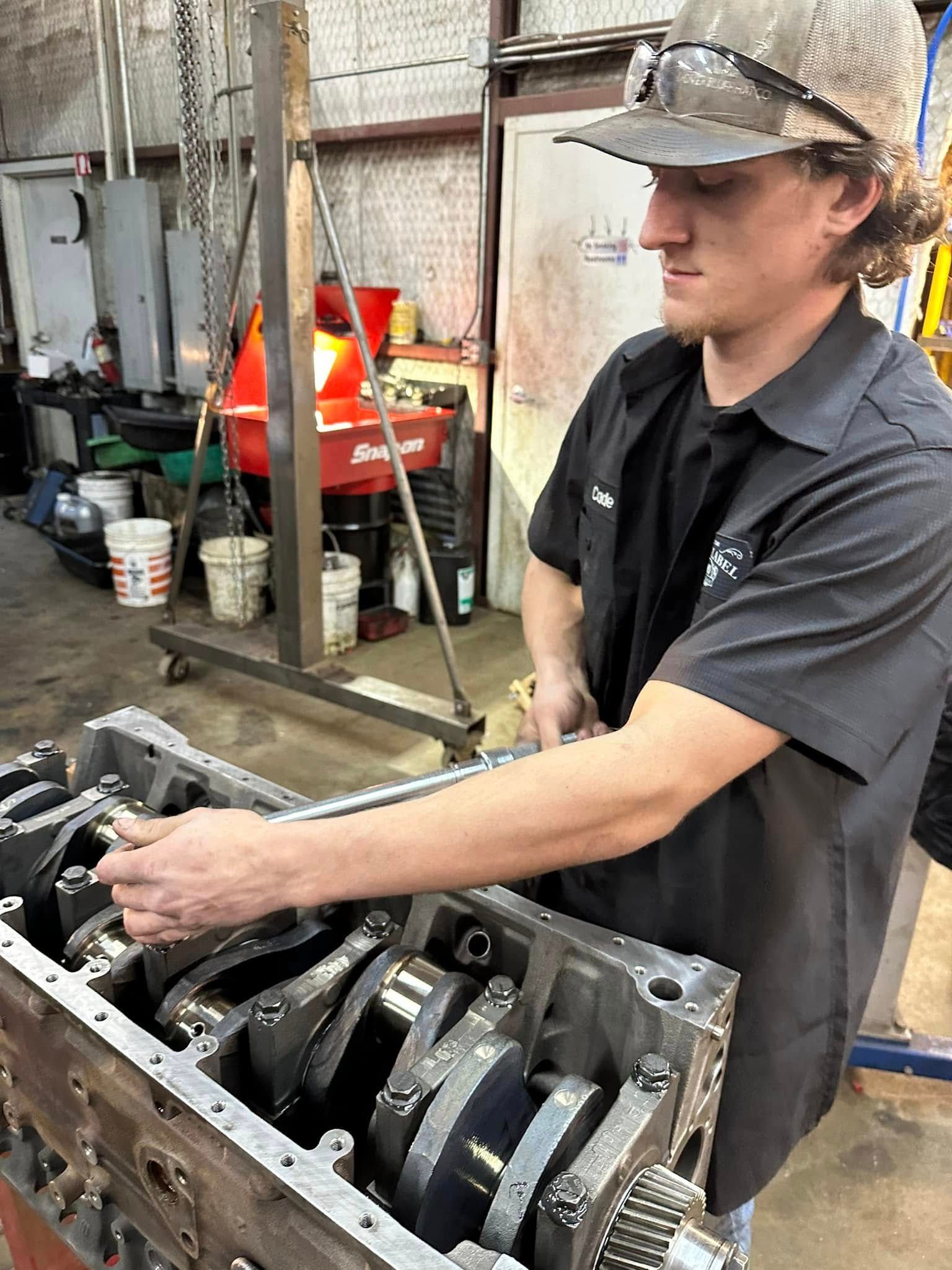 A man in a hard hat is working on a machine in a garage.