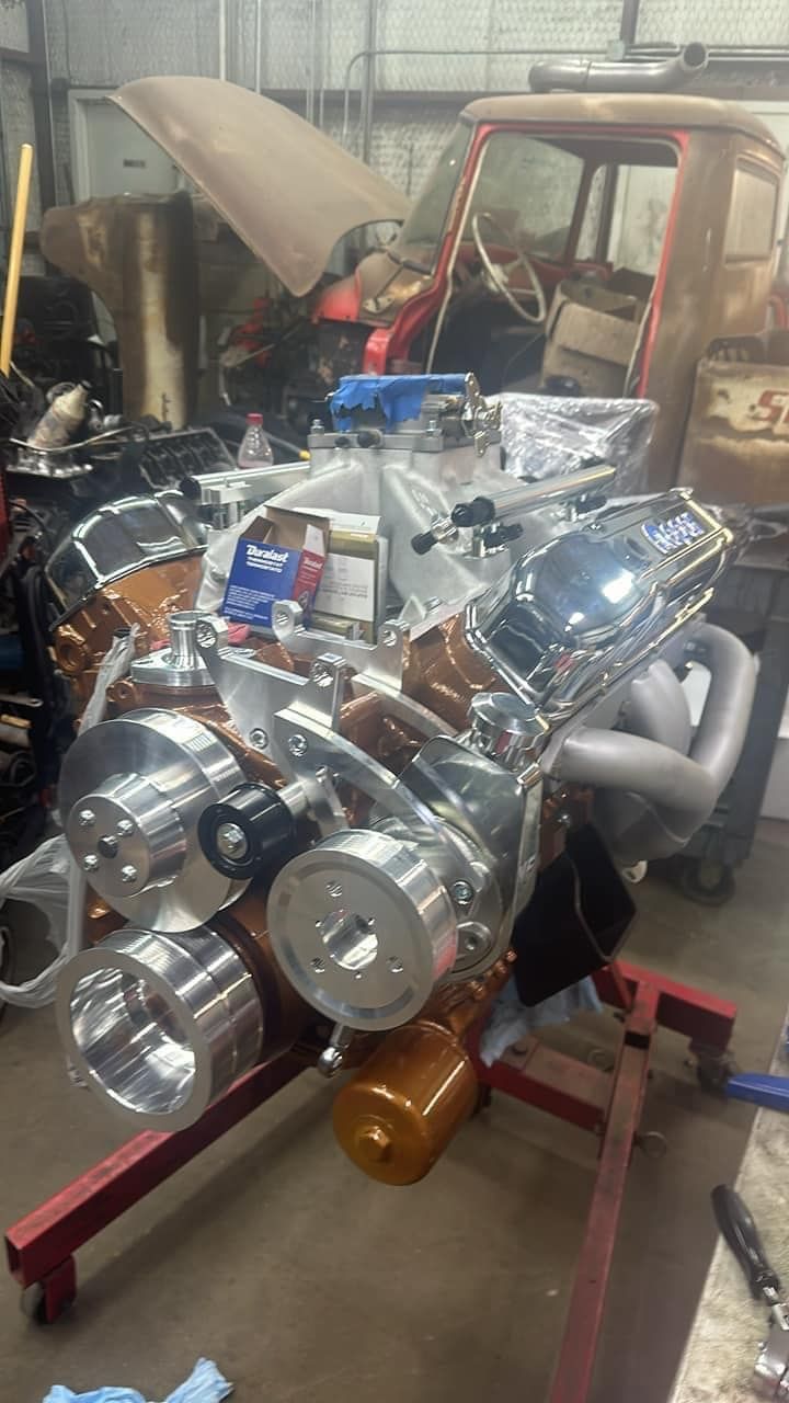 A car engine is sitting on top of a red engine stand in a garage.