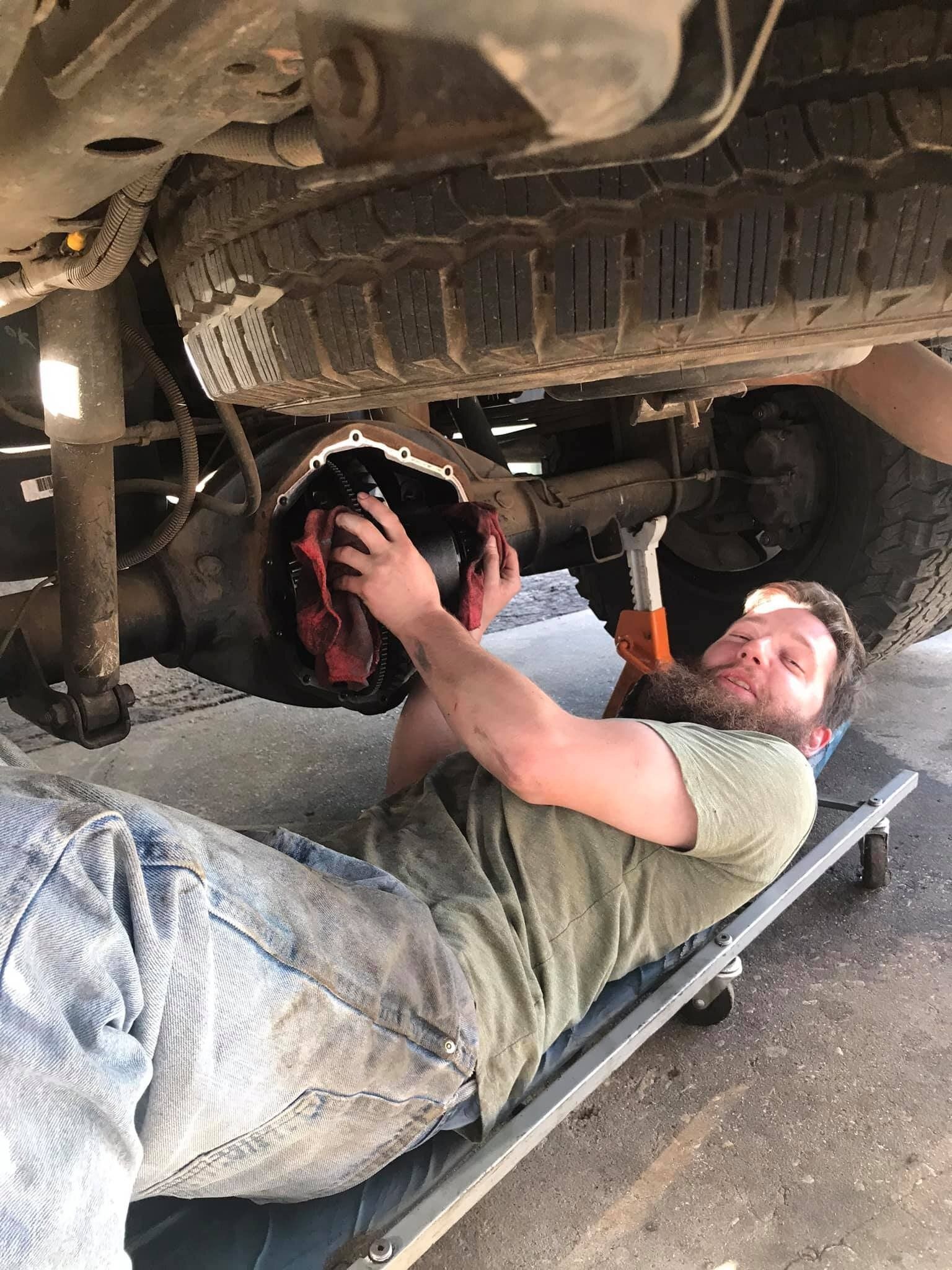 A man is laying on a stretcher under a truck.