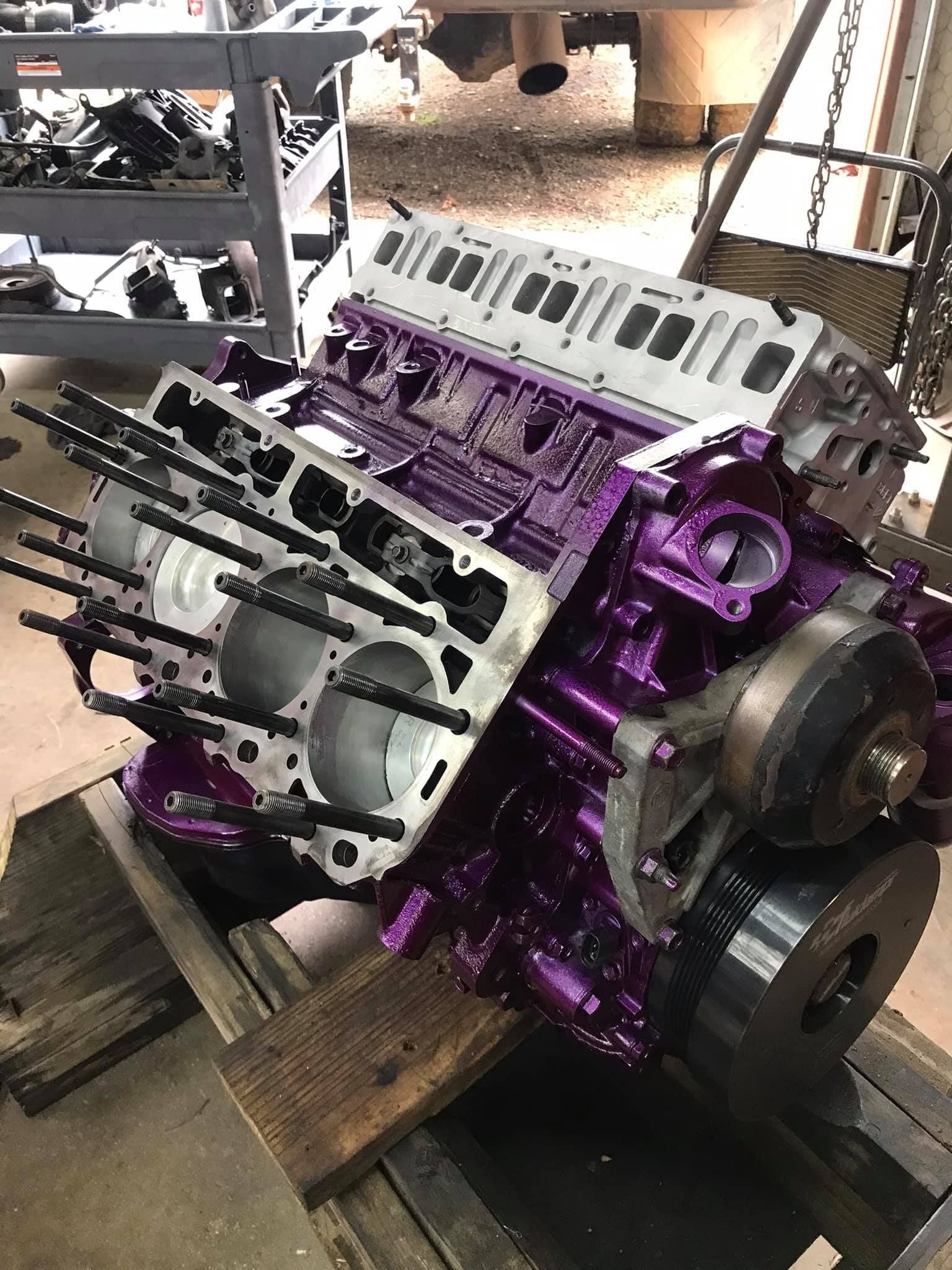 A purple engine is sitting on top of a wooden table.