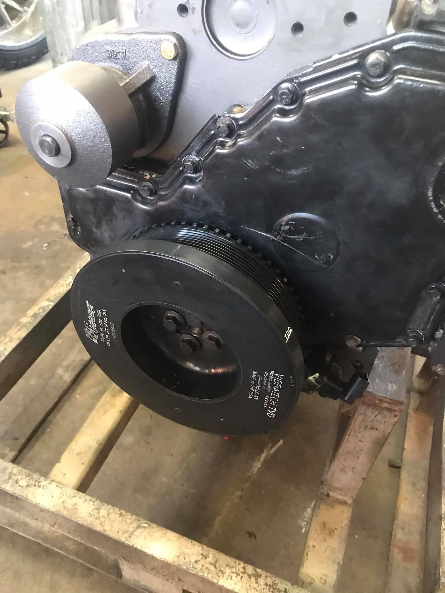 A black engine is sitting on top of a wooden pallet.