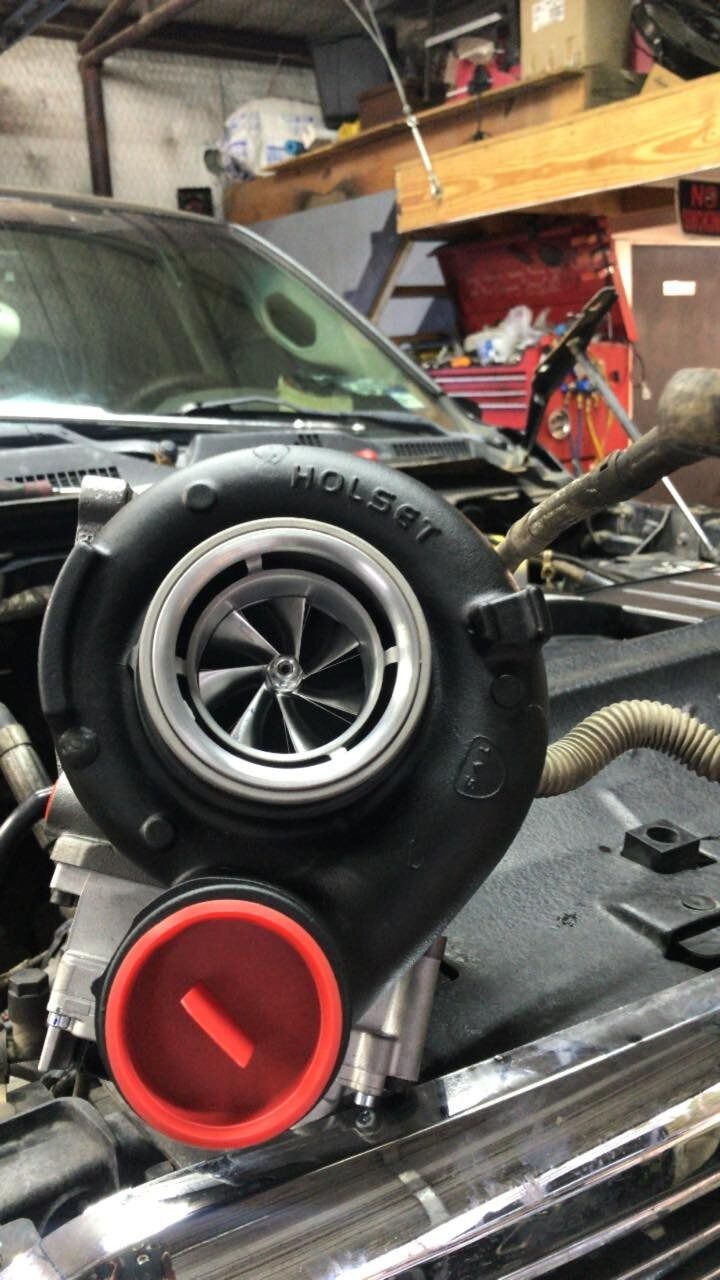 A turbocharger is sitting on top of a car engine.