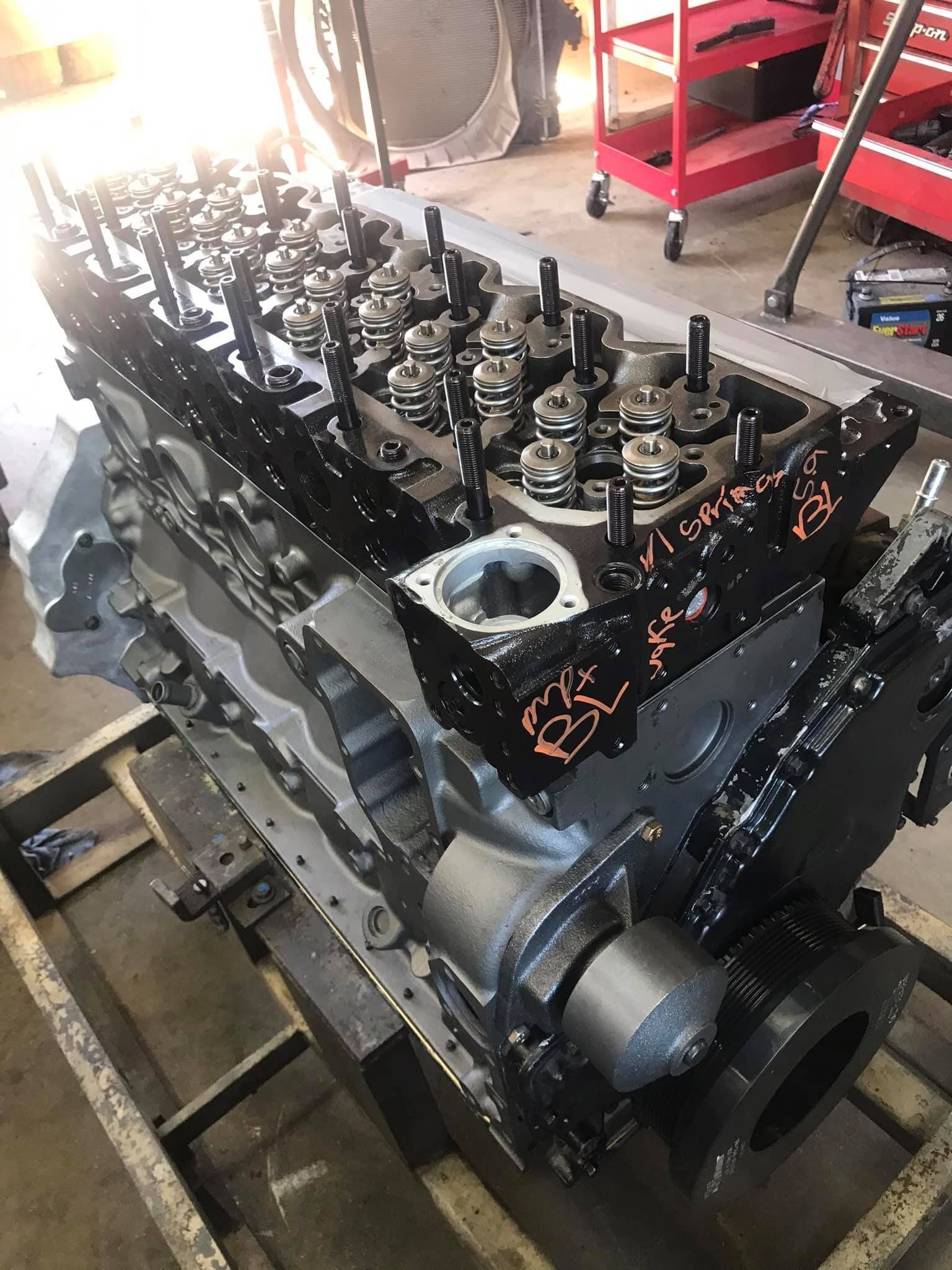 A large engine is sitting on top of a wooden table in a garage.