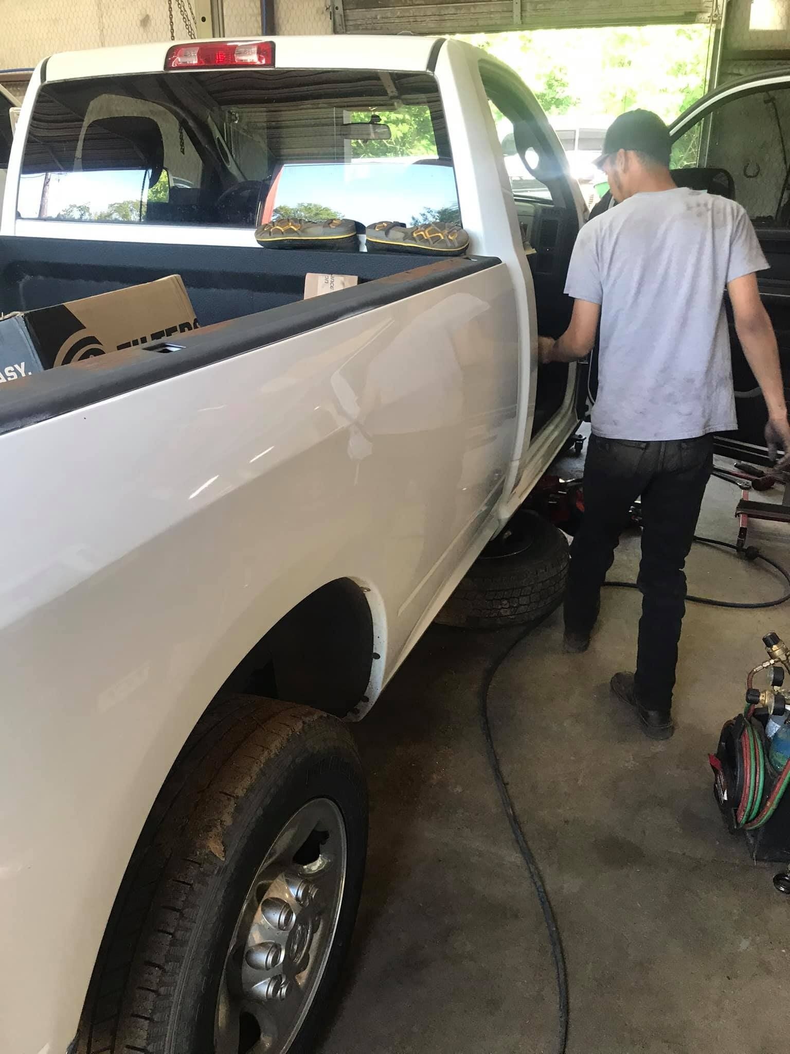 A man is working on a white truck in a garage.