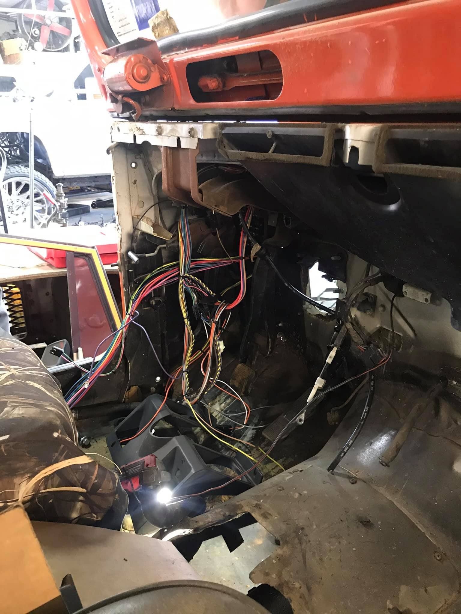 A car with the hood open and a lot of wires coming out of it.