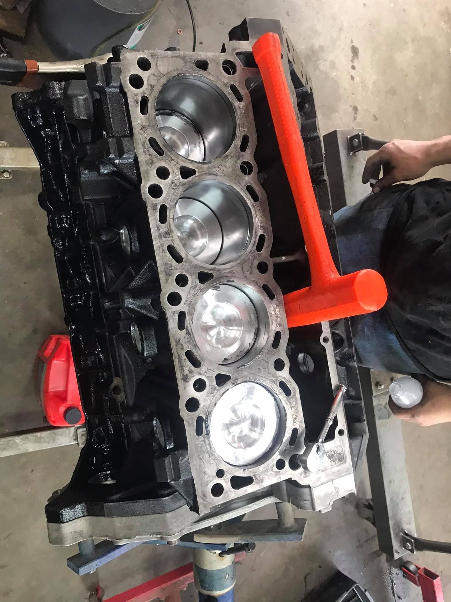 A man is working on a car engine in a garage.