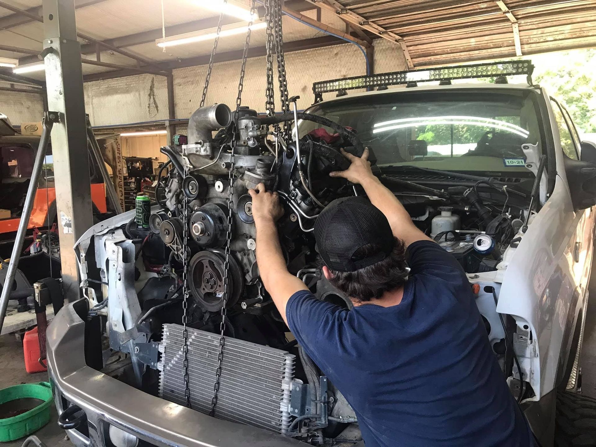 A man is working on a truck engine in a garage.