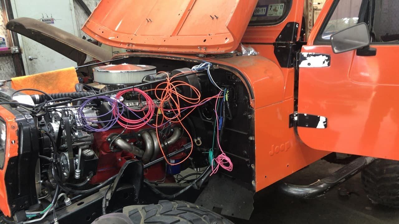 The hood of an orange truck is open and the engine is visible.