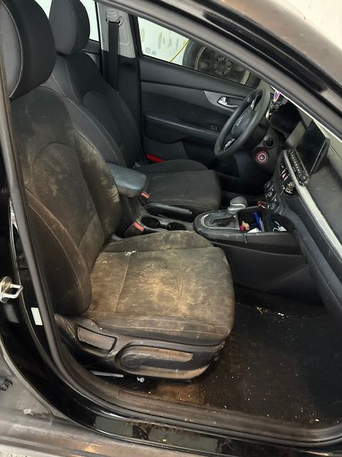 Interior of a black car with very dirty front seats and floor.