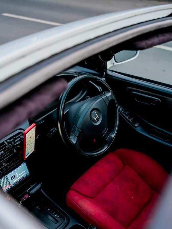 Interior view of a car featuring a red seat, black steering wheel with Honda emblem, and a partially open sunroof.