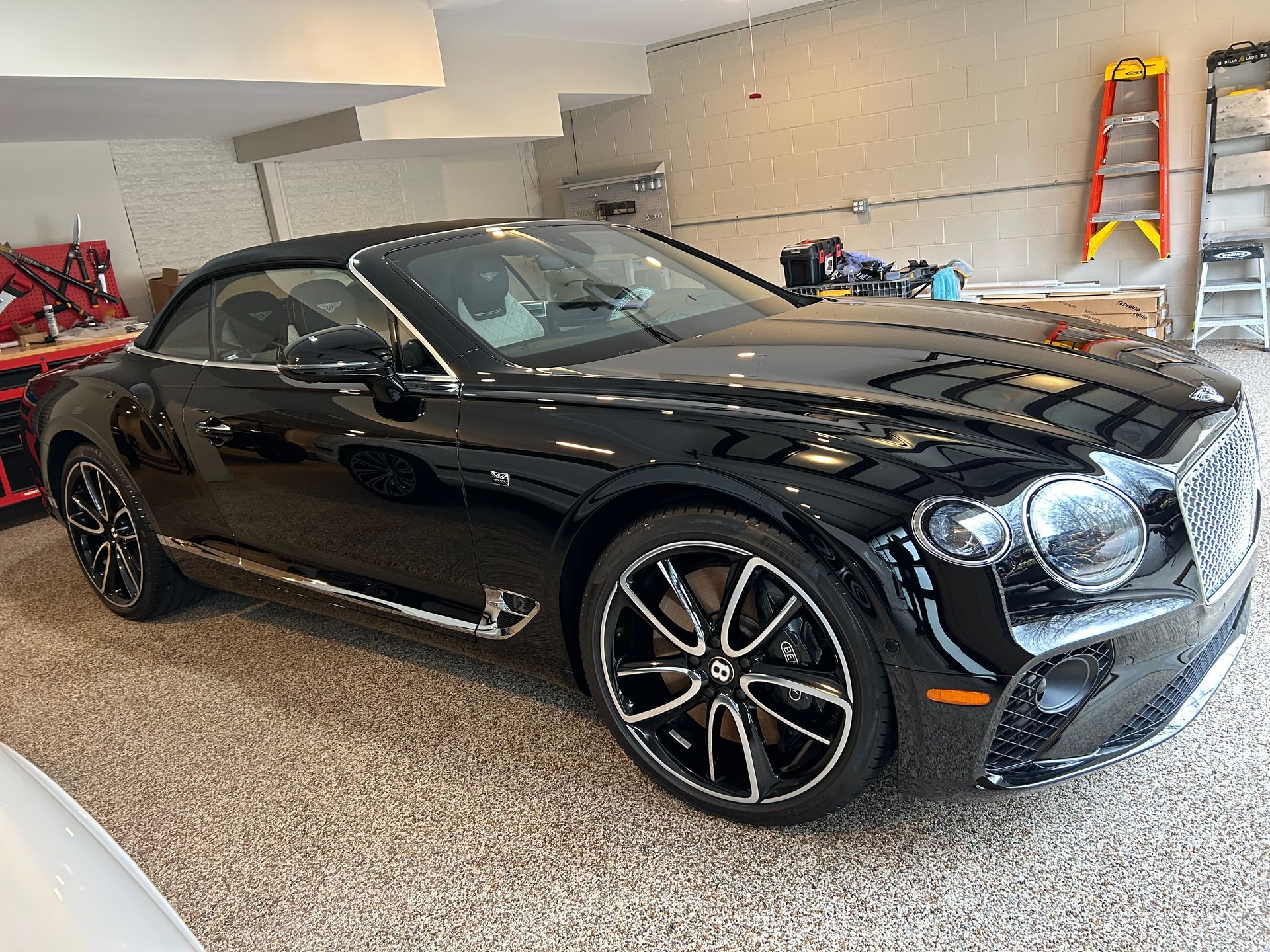 Black classic car with white stripe in a garage. Chrome wheels.