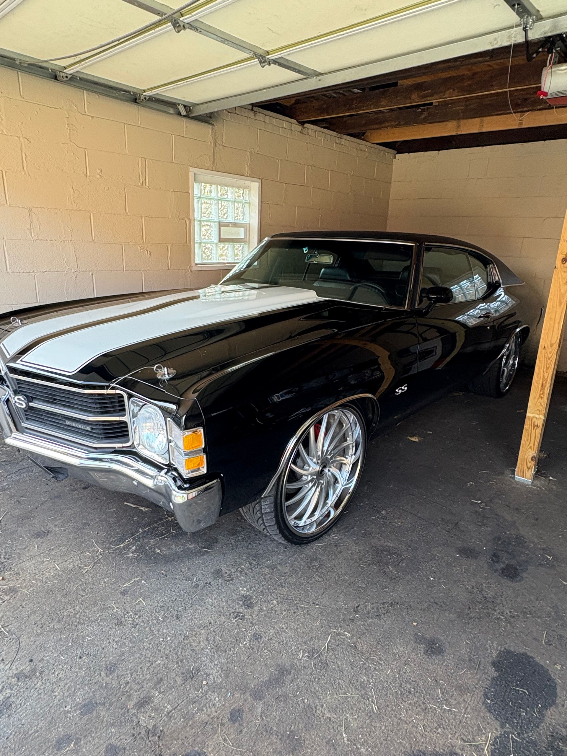 Black classic car with white stripe in a garage. Chrome wheels.