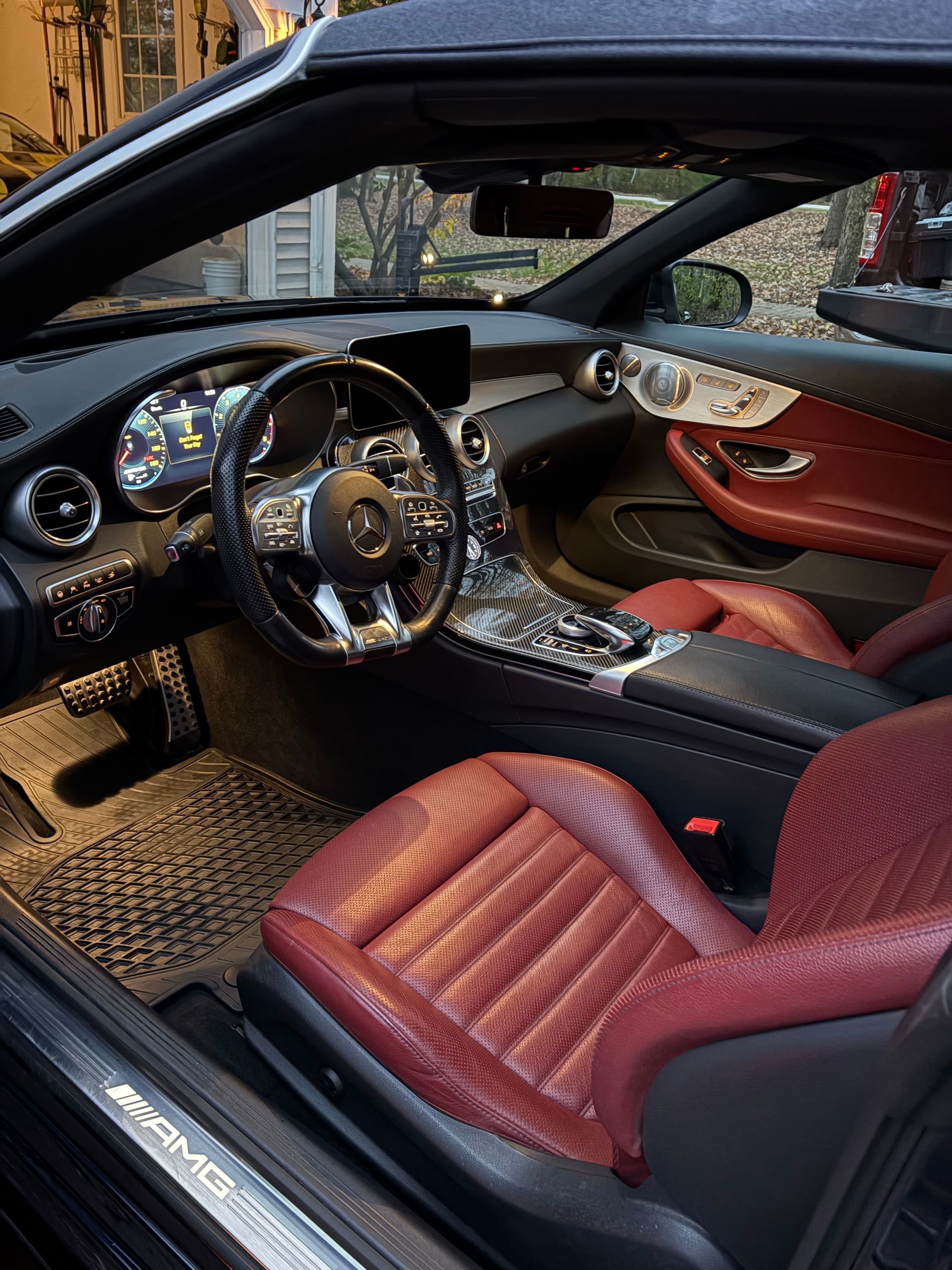 A person wearing a black glove vacuums the brown carpet inside a car, near the 