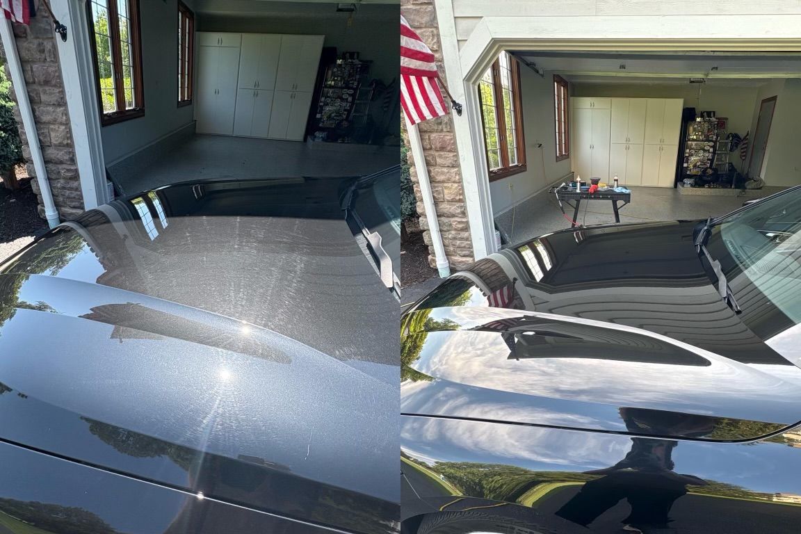 Cleaning a black car rim with a brush and soapy foam.