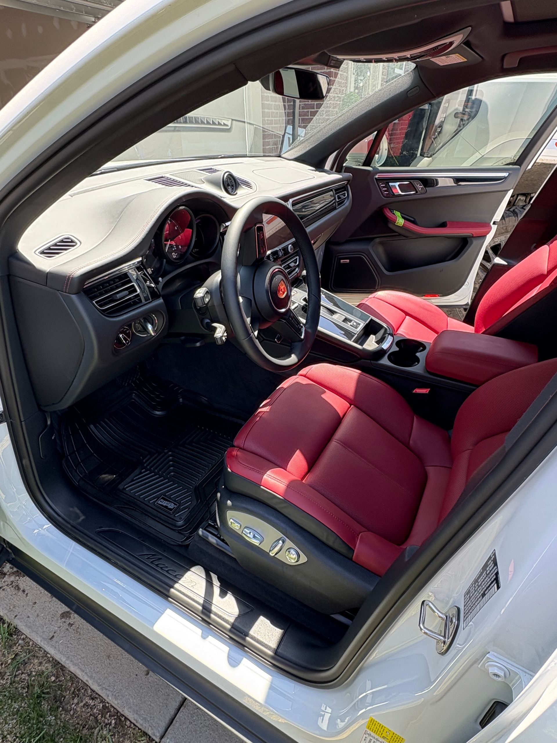 Interior of a white Porsche with red leather seats and black steering wheel.