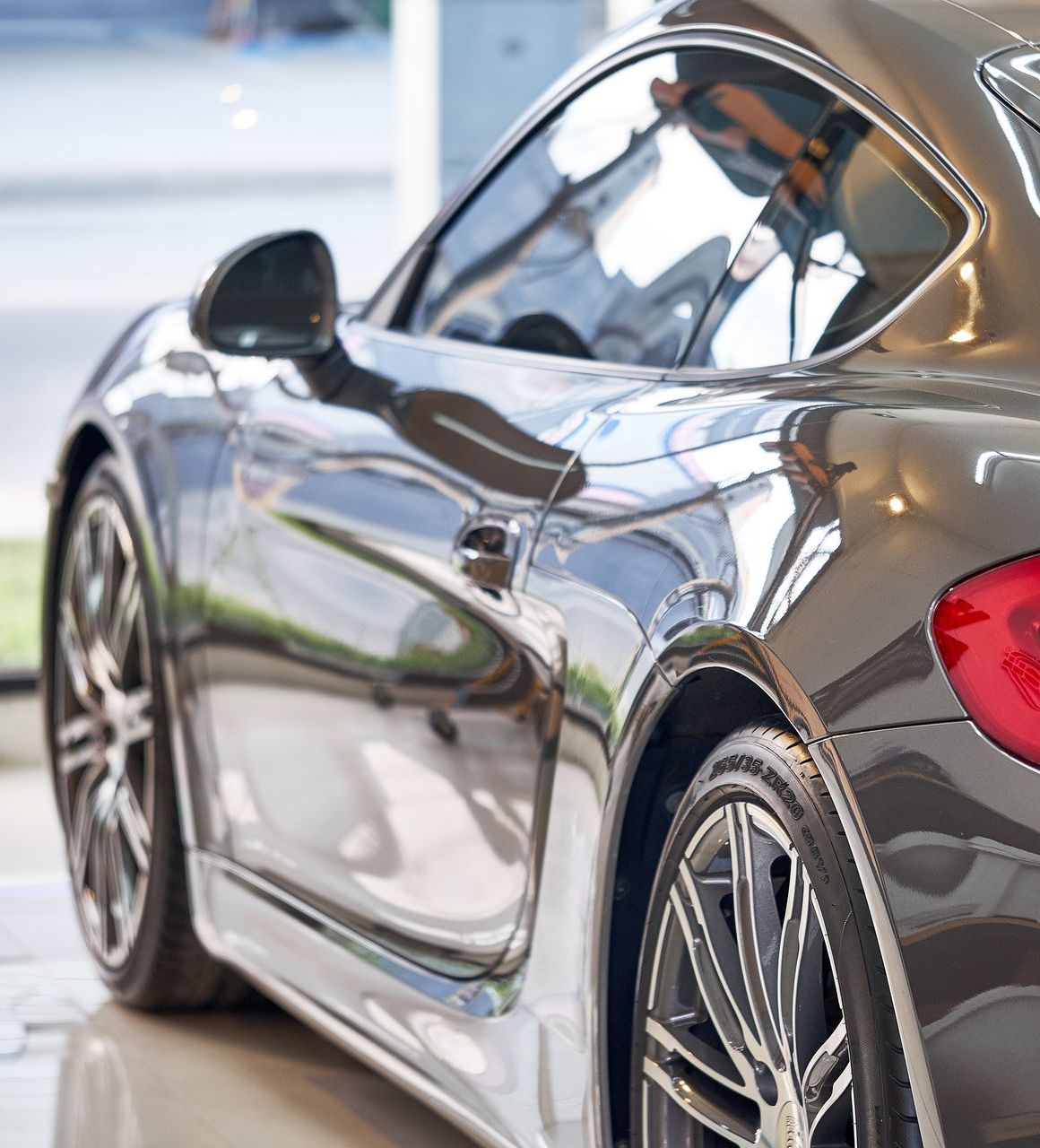 Sleek gray sports car on display, reflecting a showroom setting.